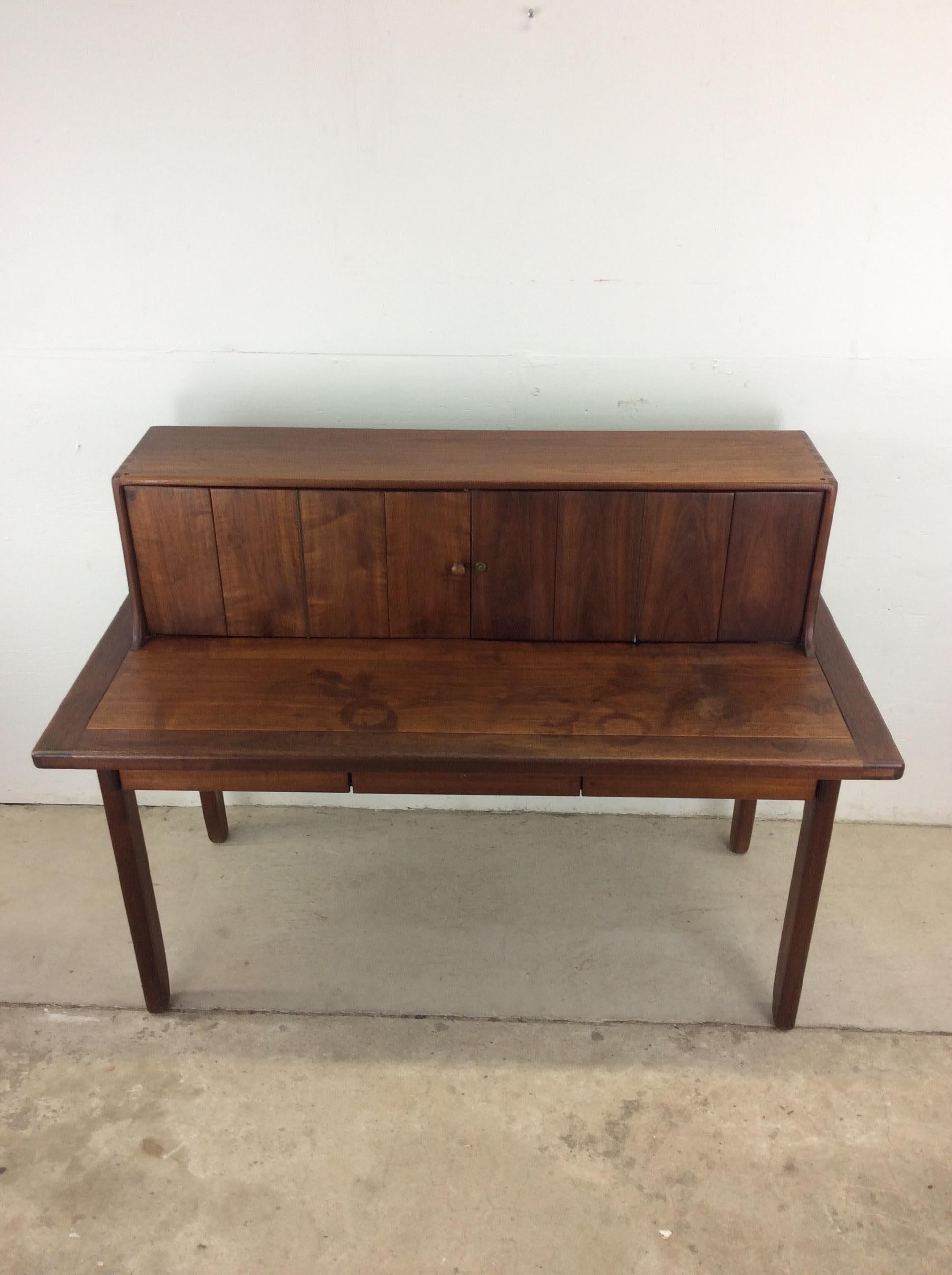 Dieser moderne Schreibtisch aus der Mitte des Jahrhunderts zeichnet sich durch eine Hartholzkonstruktion, eine originale Walnussoberfläche, Flügeltüren oben mit 8 schwalbenschwanzförmigen Schubladen und offenem Stauraum, drei schwalbenschwanzförmige