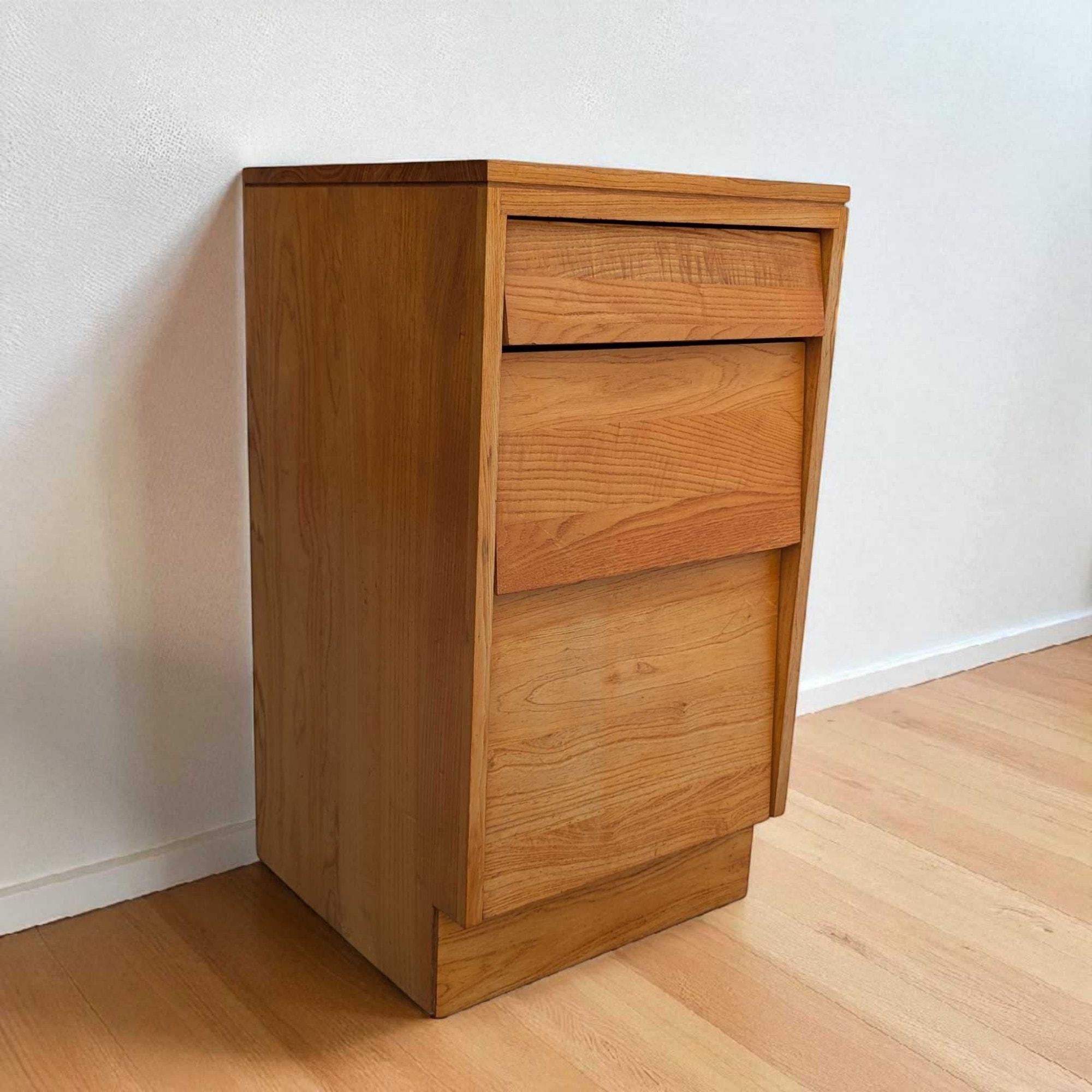 Cette élégante table de nuit en bois massif de Woodland Furniture Co. présente un profil épuré avec trois tiroirs et des poignées intégrées pour un look homogène.

Influences marquantes du design - Moderne du milieu du siècle, Moderne de Californie.