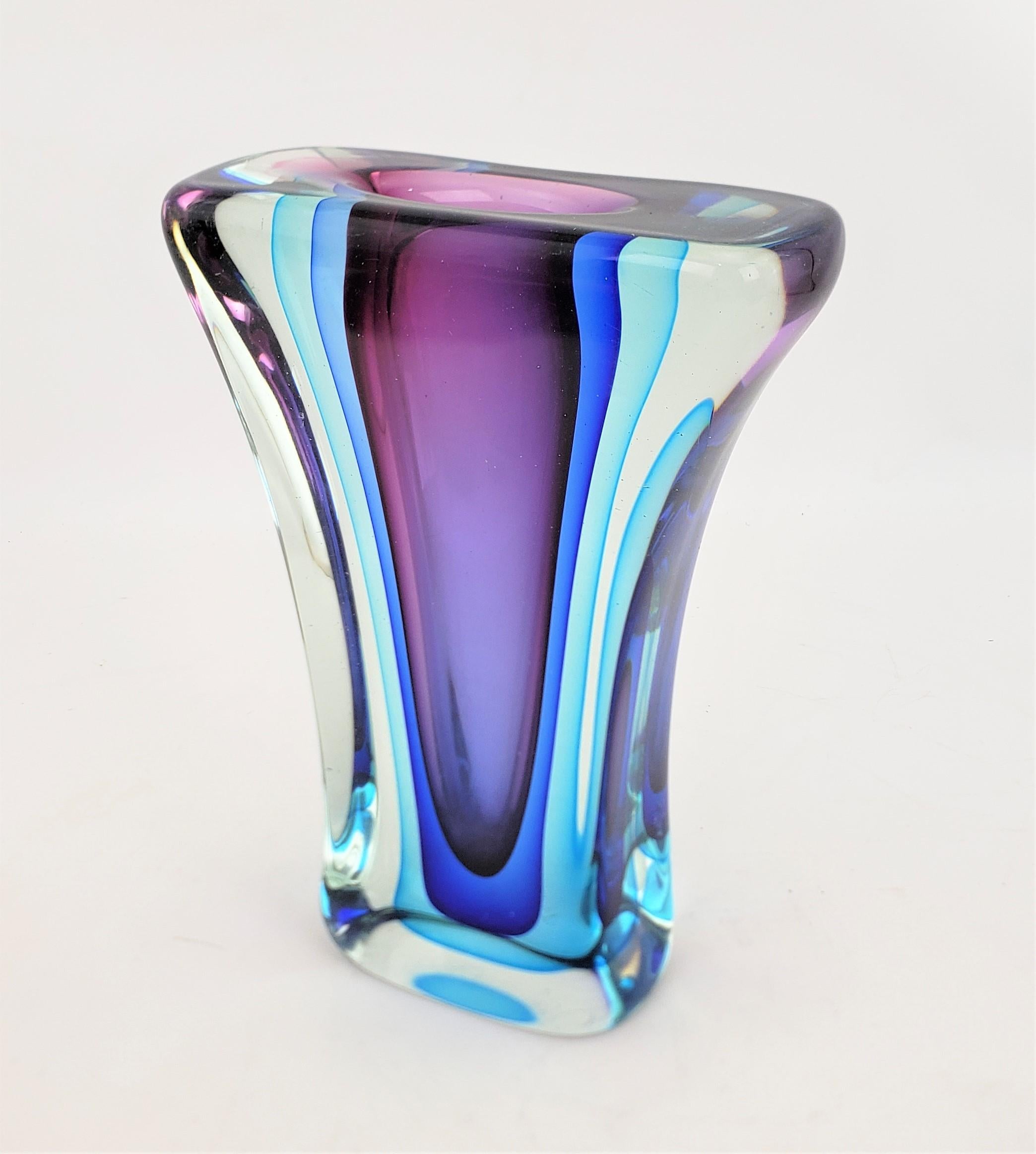 This very well executed art glass vase is unsigned, but presumed to have originated from Italy and dating to approximately 1967, and done in the period Mid-Century Modern style. The vase is done with a thick clear, almost slab of clear glass, which