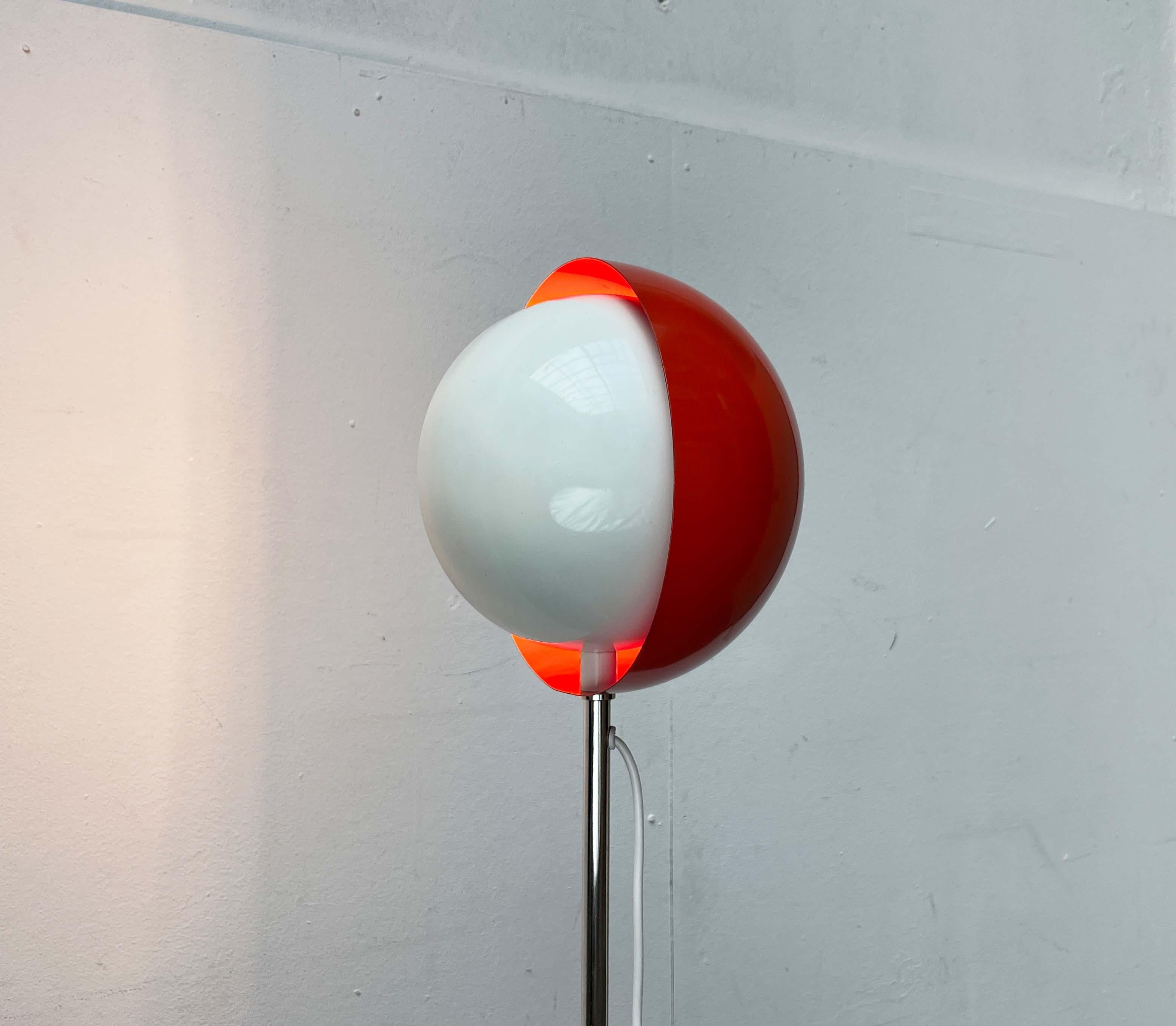 Rare Space Age floor lamp with an eclipse effect.

The spherical reflector sits at the top of a long shaft. It consists of two half-shells, one fixed and one adjustable. The inner shell is white and supports the lamp socket in the center. The outer