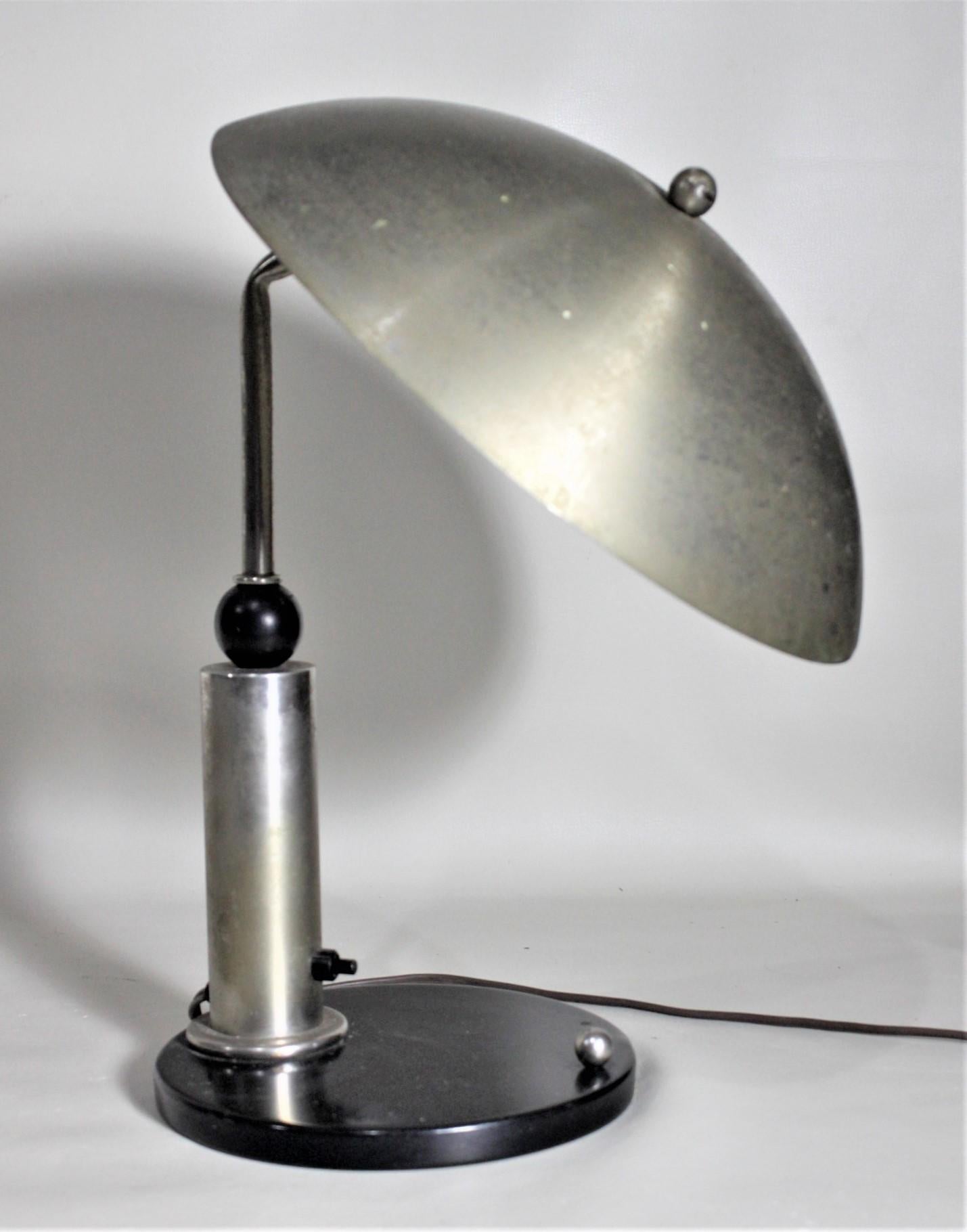 This Mid-Century Modern desk or table lamp is completely unsigned, but believed to have been made in the United States in circa 1965. The lamp is done in the space age, flying saucer style with a brass finished metal shade, tubular post and circular