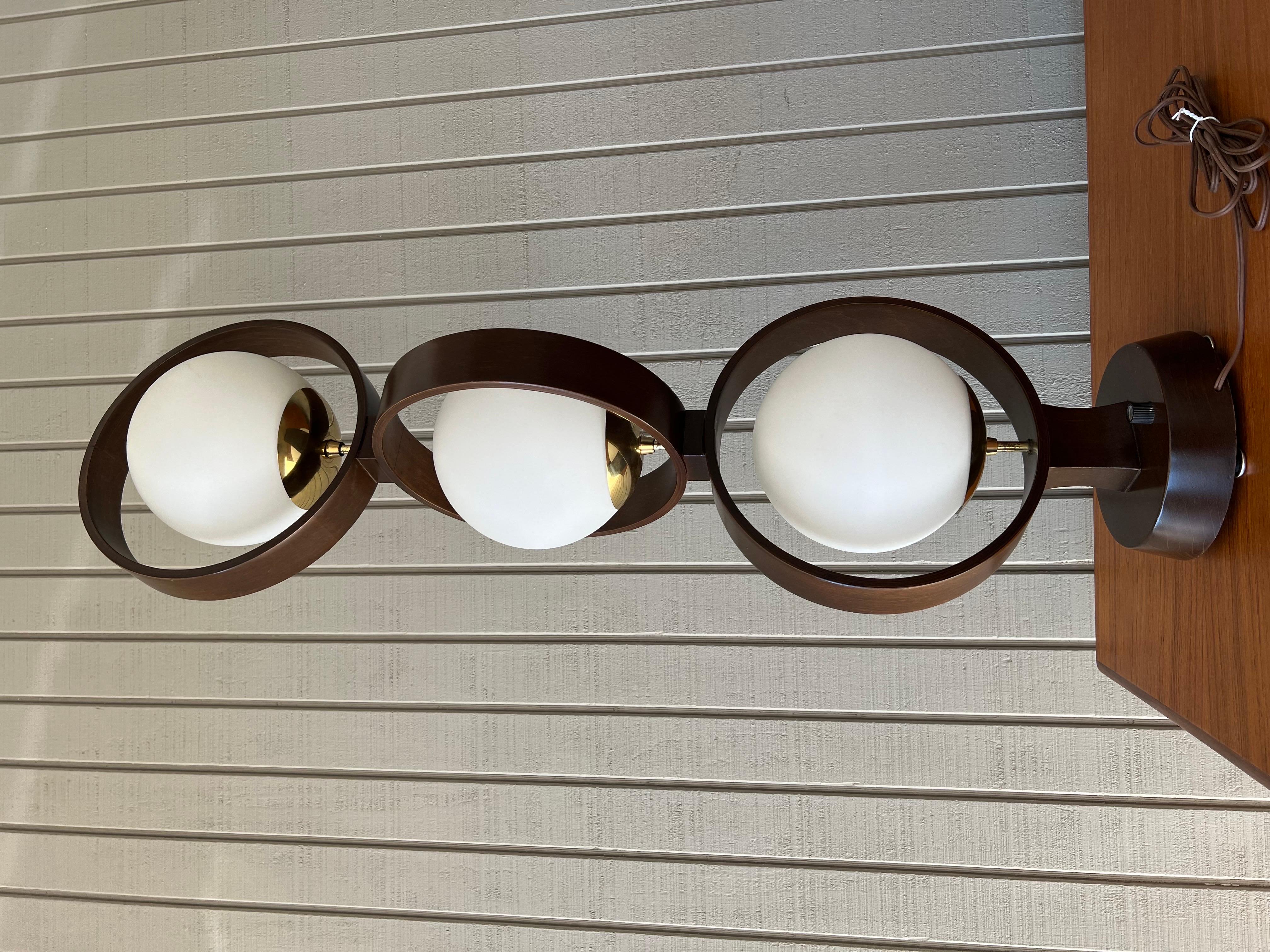 Large mid century modern triple globe and ring lamp designed by Arthur Jacobs for Modeline in the 1960s. Three glass globes with brass accents are held in place by a walnut frame and base. The wiring was cleverly integrated into the bent wood. This