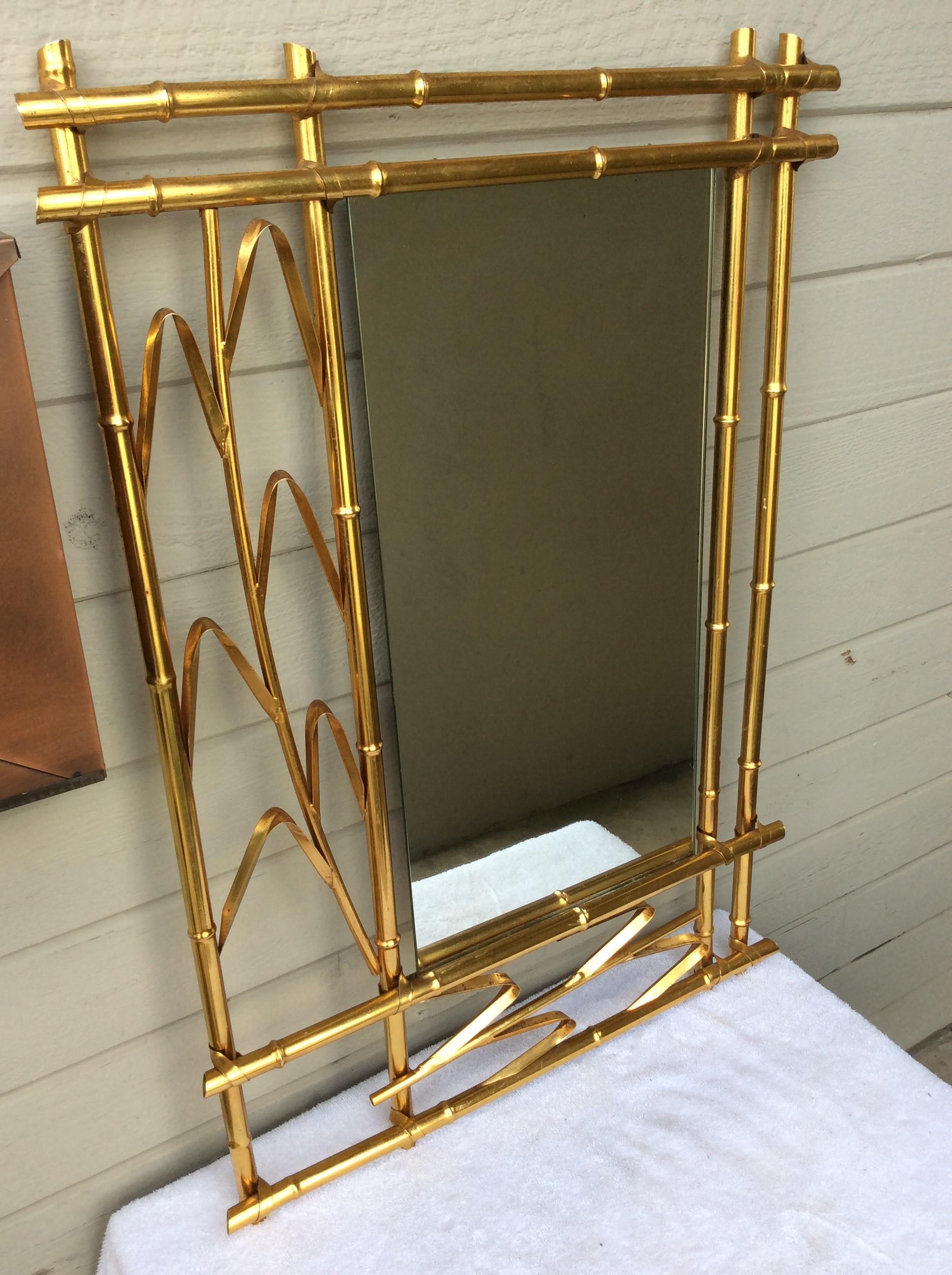 This Mid-Century Modern Spanish Brass Faux Bamboo Mirror features brass over metal with stems of leaf motifs on the side and bottom. Rectangular in shape the elegant design of this mirror allows it to be displayed vertical or horizontal. Constructed