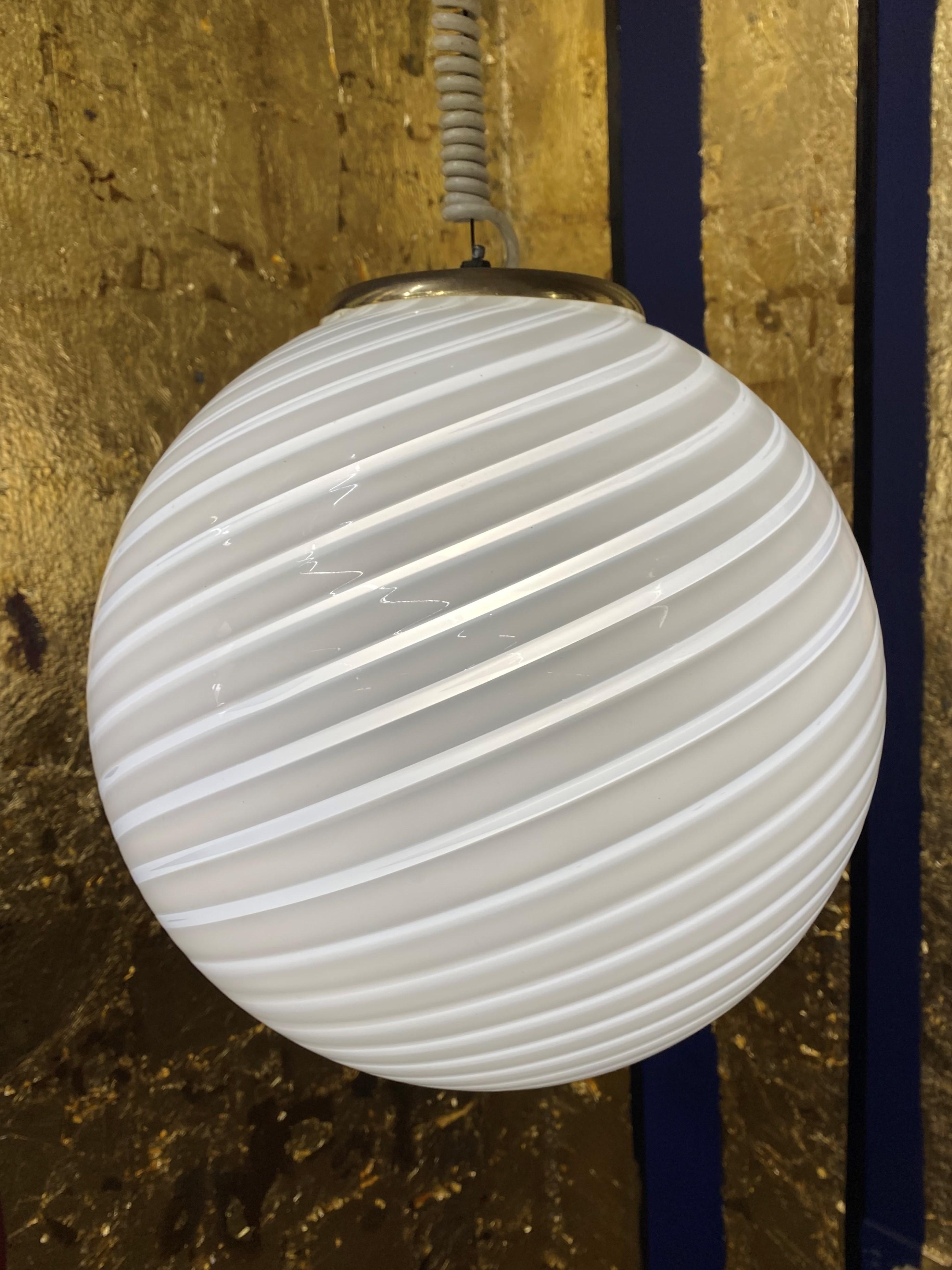 Space Age pendant light manufactured in white and clear striped hand blown Murano glass, attributed to Venini, circa 1970.
Measures: Diameter is 33cm.
Height is 60cm but can be easily adjusted to measure.
The coiled cable is original to the lamp
