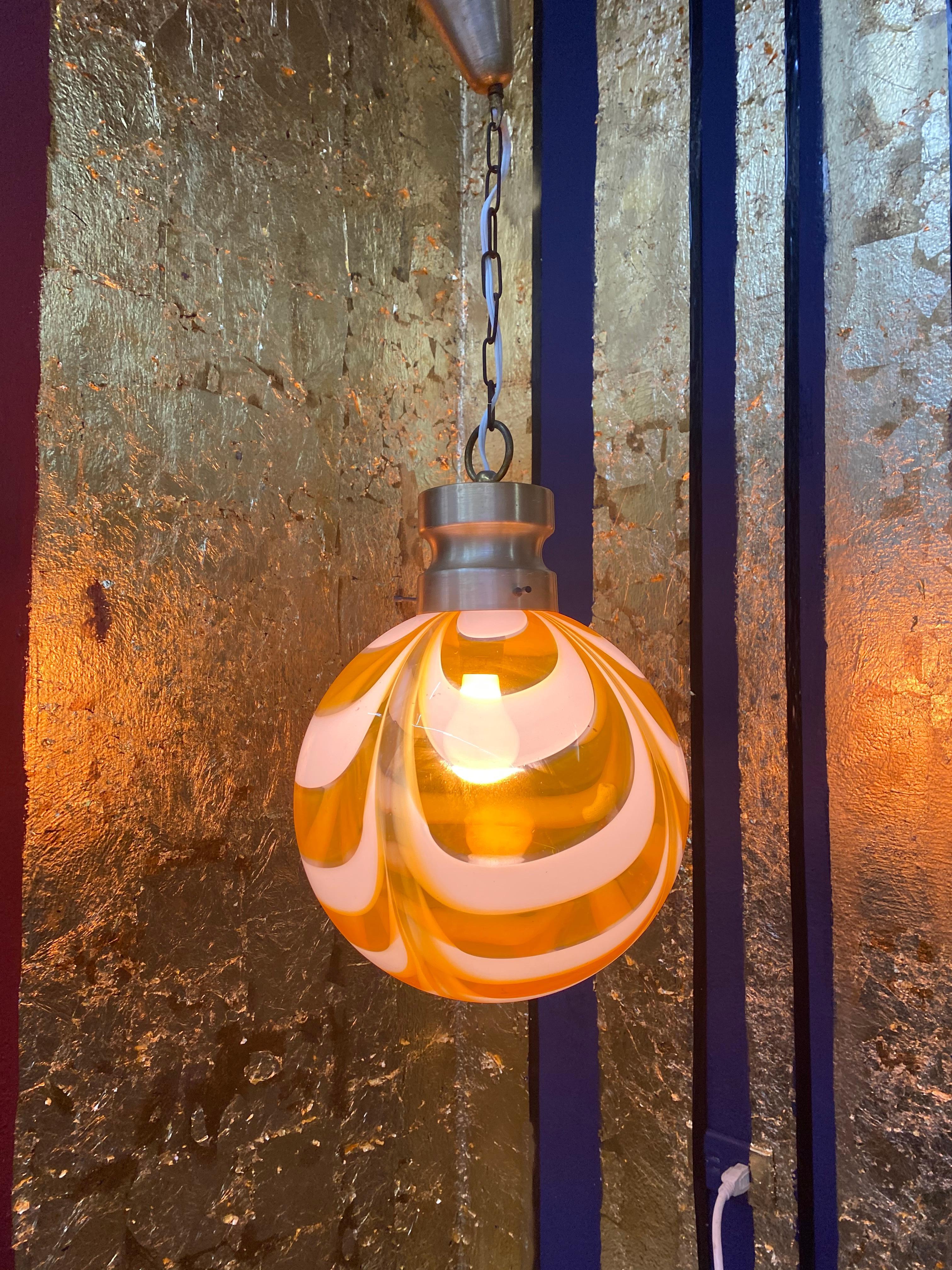 Space Age pendant light manufactured in white and orange swirled hand blown Murano glass, attributed to Venini, circa 1970.
Measures: Diameter is 29 cm.
Height is 80 cm but can be easily adjusted to measure.
 