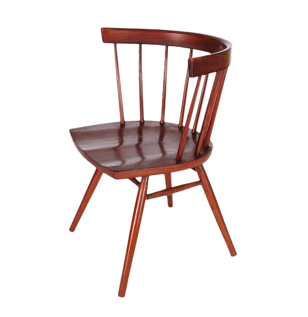 A classic George Nakashima design, the spindle back straight chair. This early 1960s example is made of cherry with signature saddle seat. Probably refinished at some point.