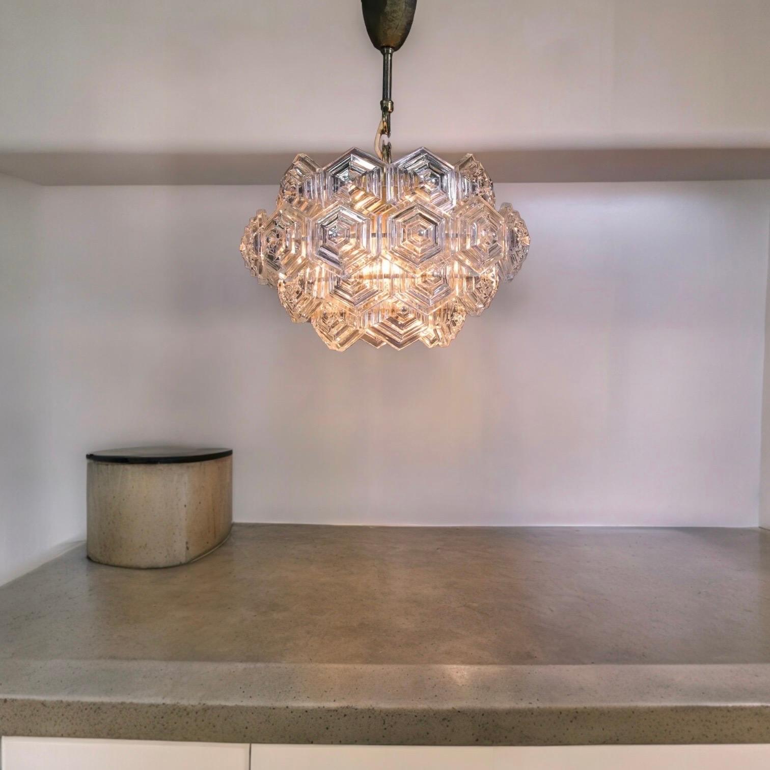 A beautiful elegant chandelier with hexagonal glass prisms on a brass frame made by VEB Kristall Leuchten in the GDR in the 1960s. The chandelier requires three European E27 / 110 Volt Edison bulbs, each bulb up to 60 watts. It is made of depression