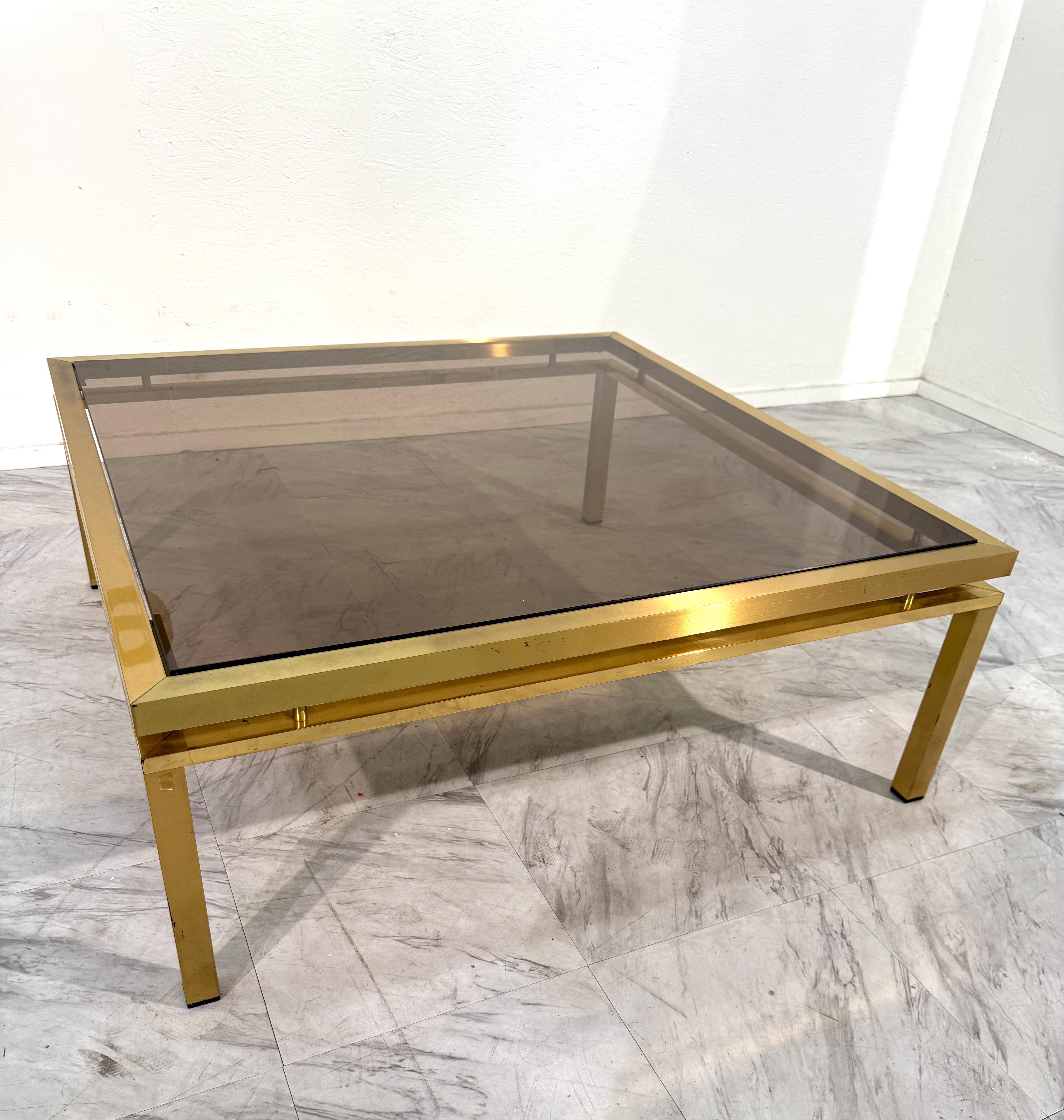 Raffinierter quadratischer Couchtisch aus der Mitte des Jahrhunderts aus den 1970er Jahren mit einem eleganten Messingrahmen mit klaren geometrischen Linien und einer Platte aus Rauchglas. Die spiegelnde Messingstruktur verleiht der Leuchte einen