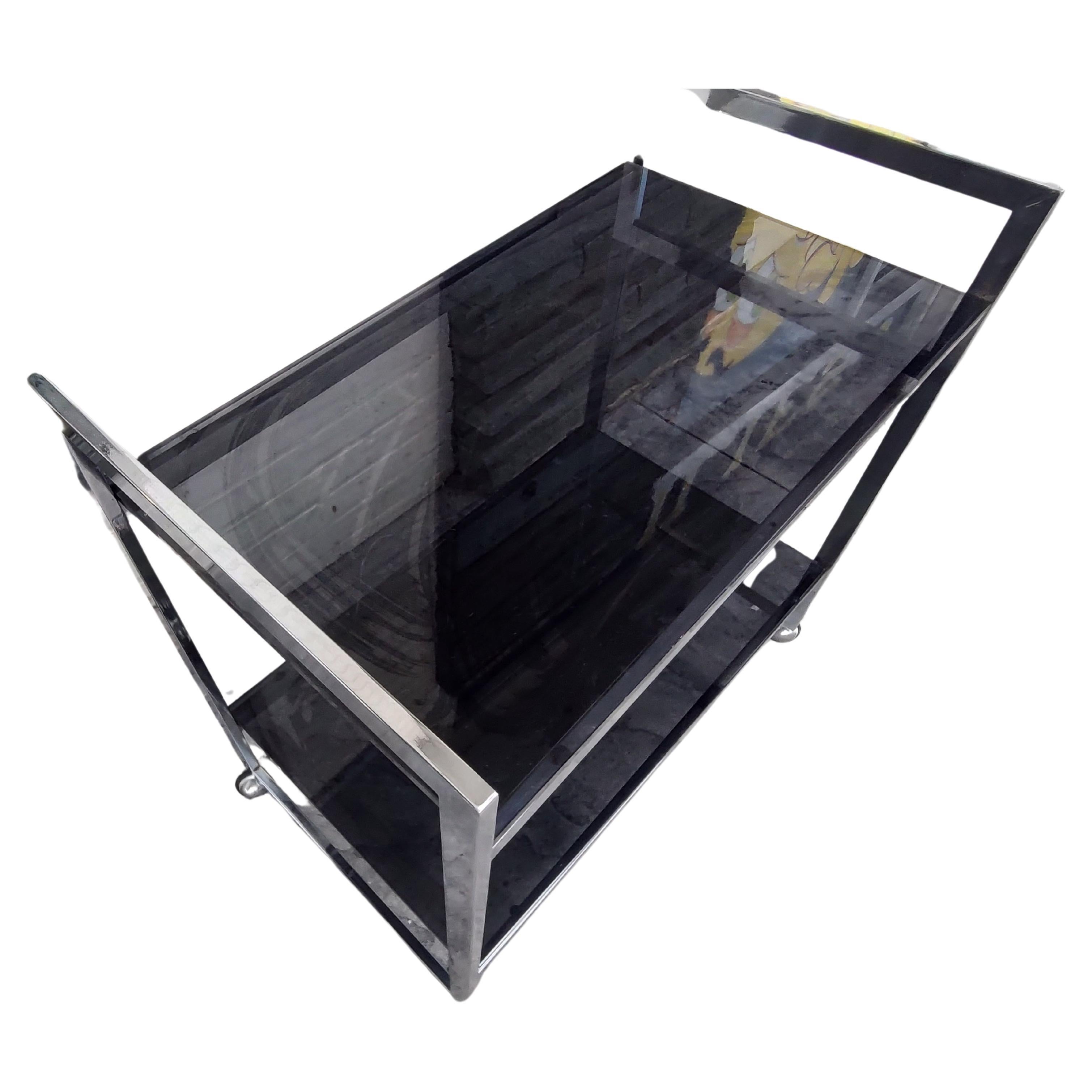 Simple and elegant chrome with black Glass bar cart. Clean straight lines keep it simple, minimalist approach is the key to the design of this bar cart. Flat bars with chromed and rubber wheels, this cart has no issues with movement. Heavy thick 1/2