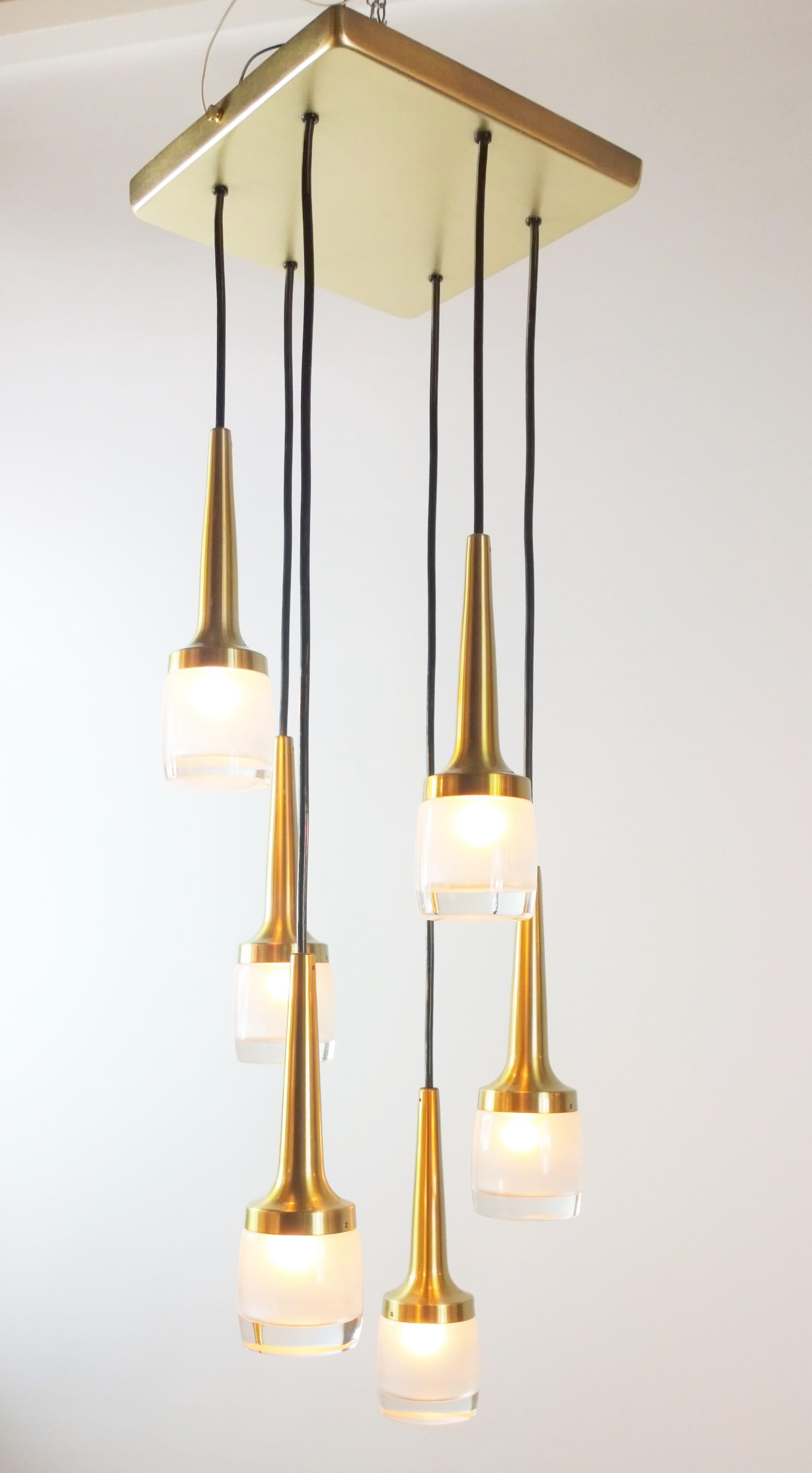 Offered is a Mid-Century Modern German Staff Leuchten six pendant molded glass and brass pendant attached by rubber cord to a brass ceiling plate chandelier. This modern, streamlined yet elegant chandelier would look fabulous with any decor and in