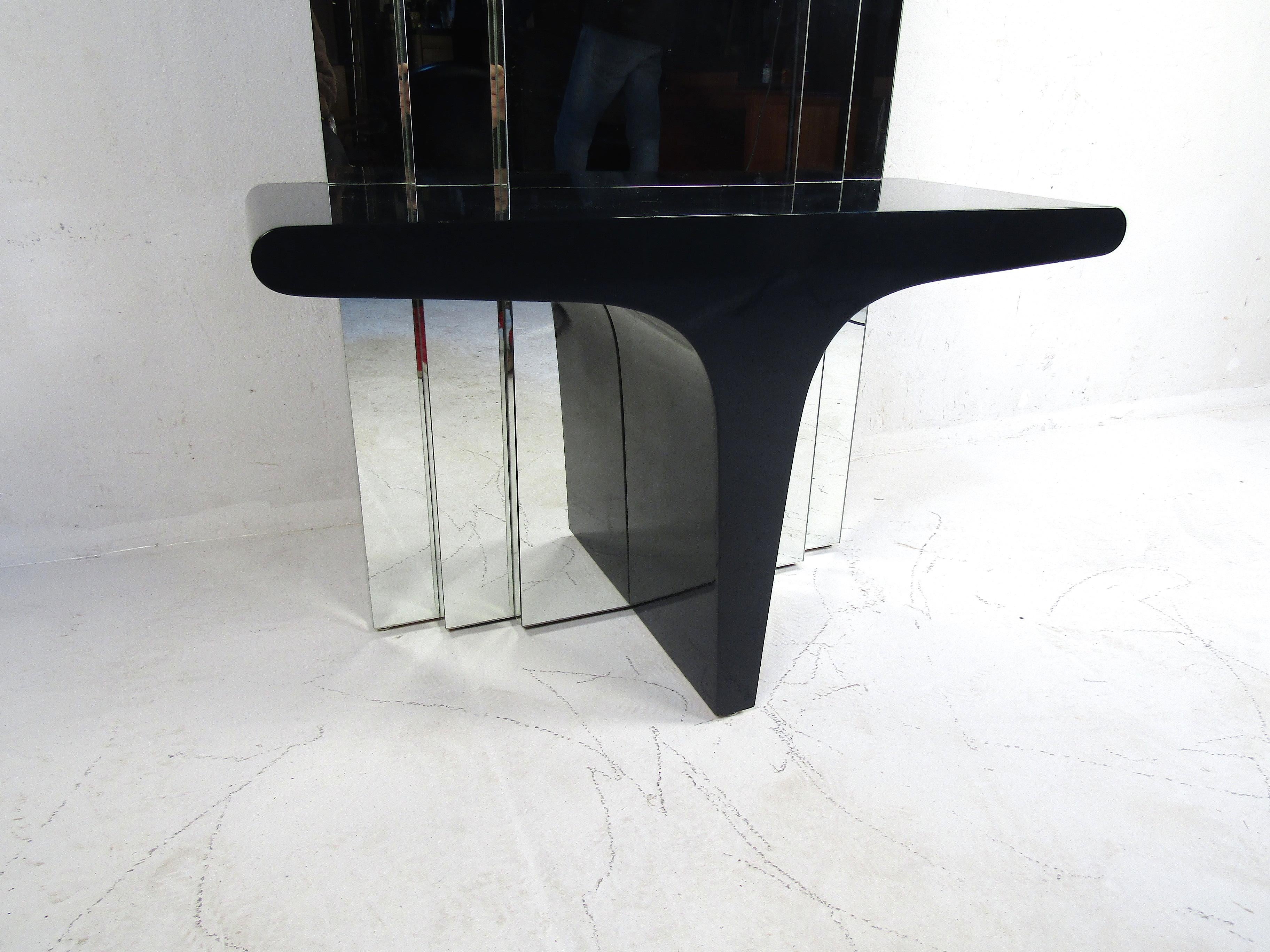 Unusual Mid-Century Modern standing mirror with a small vanity table towards the base. Interesting design with staggered tiers of mirror paneling. Small table surface with a black lacquered finish. This standing mirror would look great in any modern