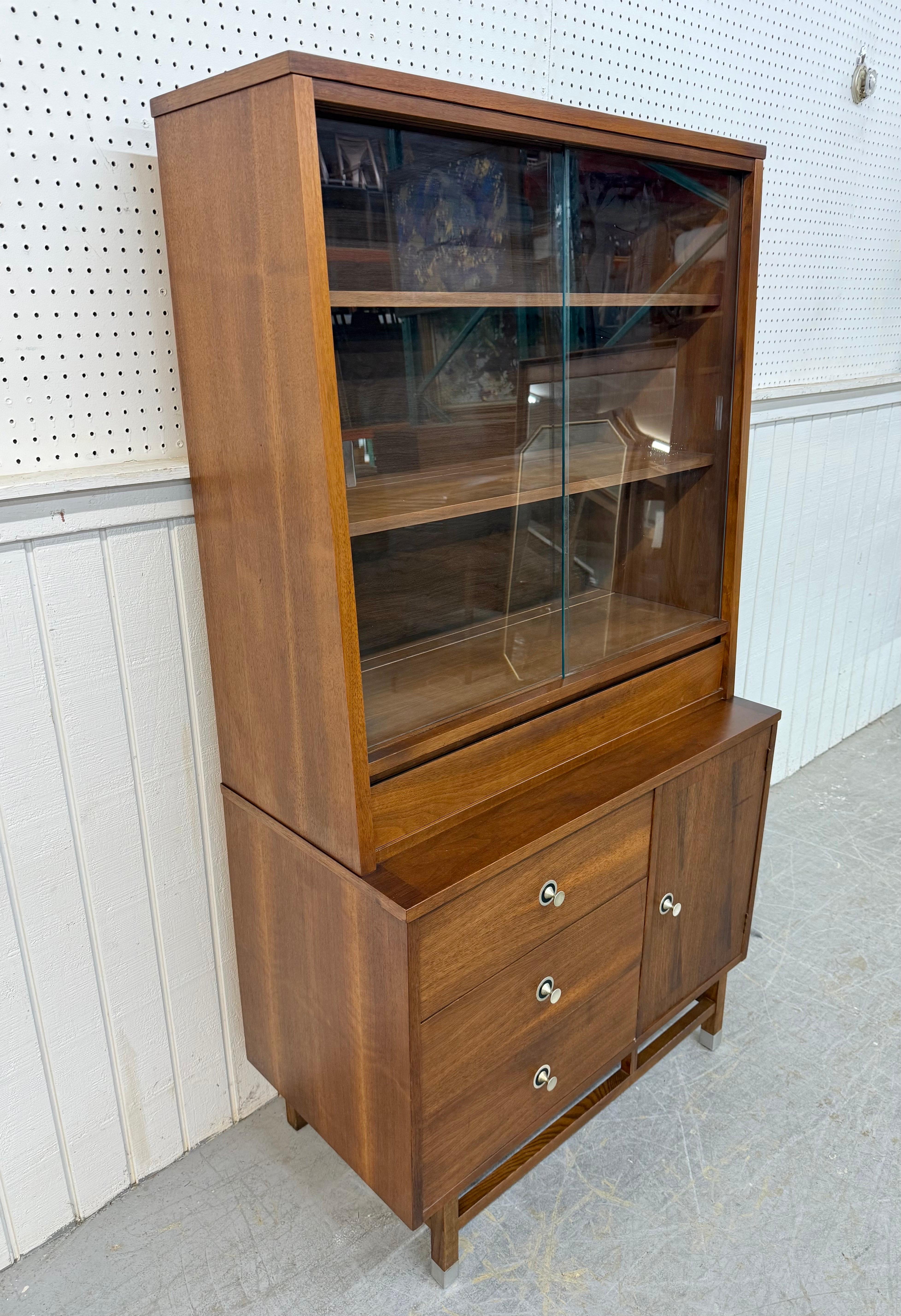 This listing is for a Mid-Century Modern Stanley Walnut Hutch. Featuring a straight line one-piece design, top has sliding glass doors that open up to storage space, single drawer with dividers, three drawers with original chrome hardware, single