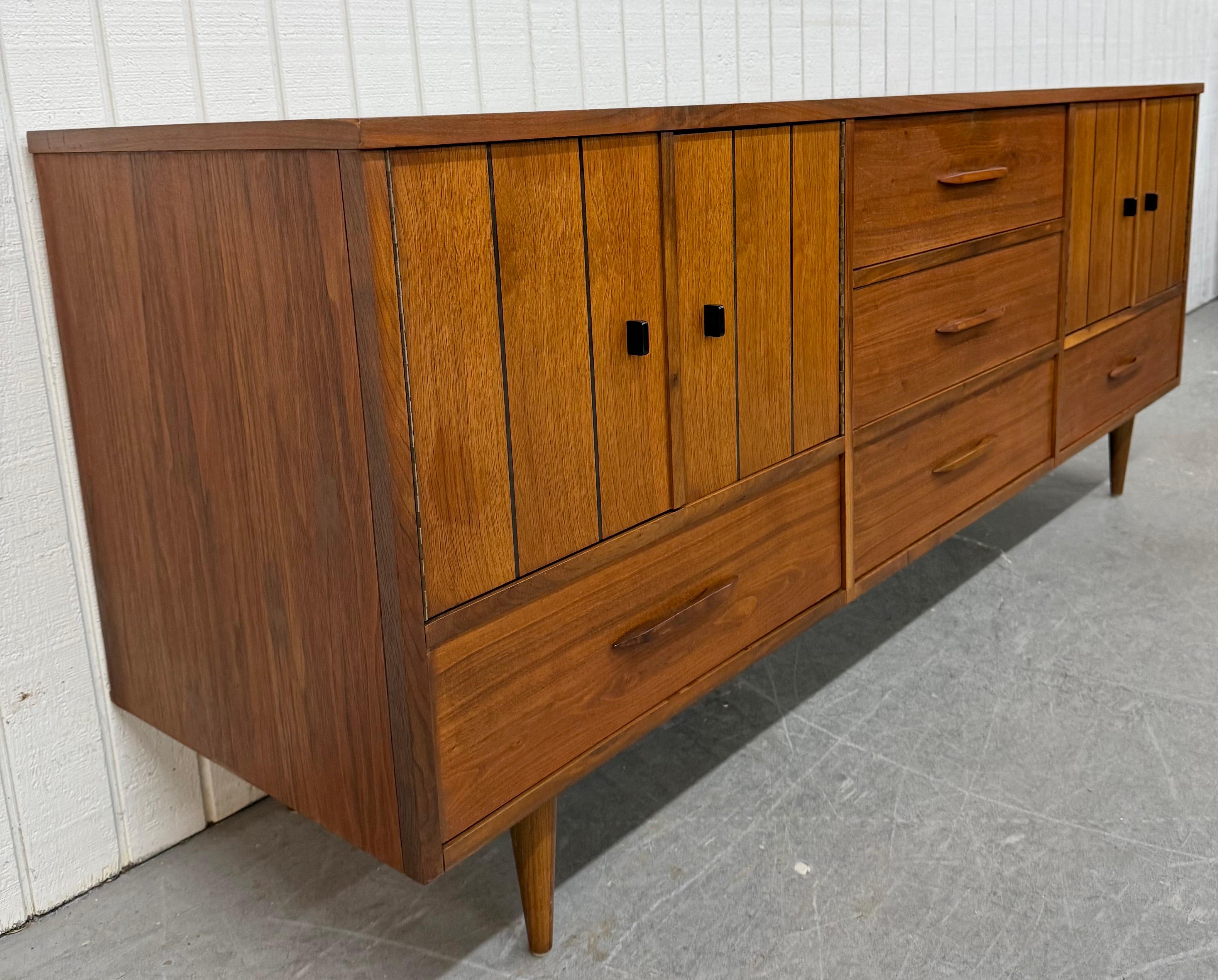 This listing is for a Mid-Century Modern Stanley Walnut Sideboard. Featuring a straight line design, doors on each side that open up to storage space, five drawers with wooden pulls, modern legs, and a beautiful walnut finish. This is an exceptional