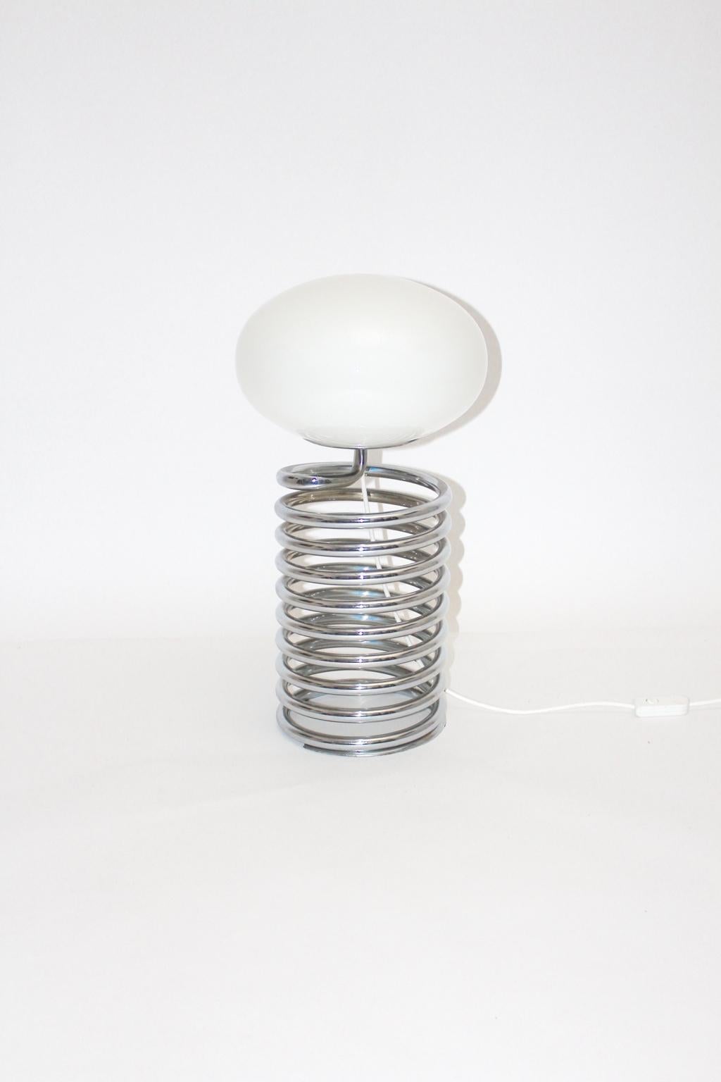 Mid Century Modern vintage chromed steel spring lamp by Ingo Maurer with an opal glass shade, Germany 1968.
The table lamp shows one E 27 socket and an on/off switch.
