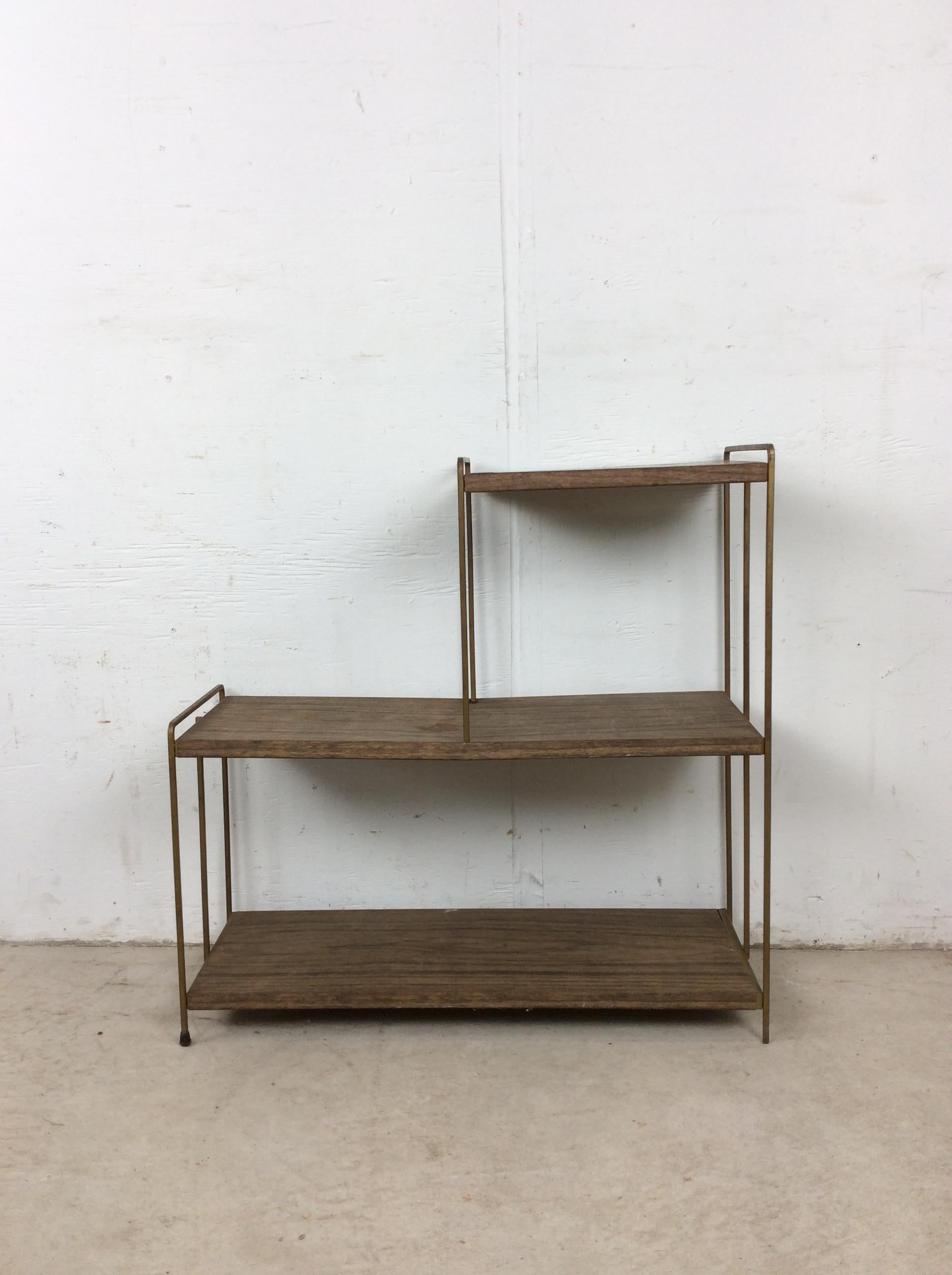 This classic mid century modern bookcase features three step metal shelves with original brown paint and faux walnut print, brass accented legs & feet.  I have three similar metal shelves with 4 shelves each. Please check out the other listings.
