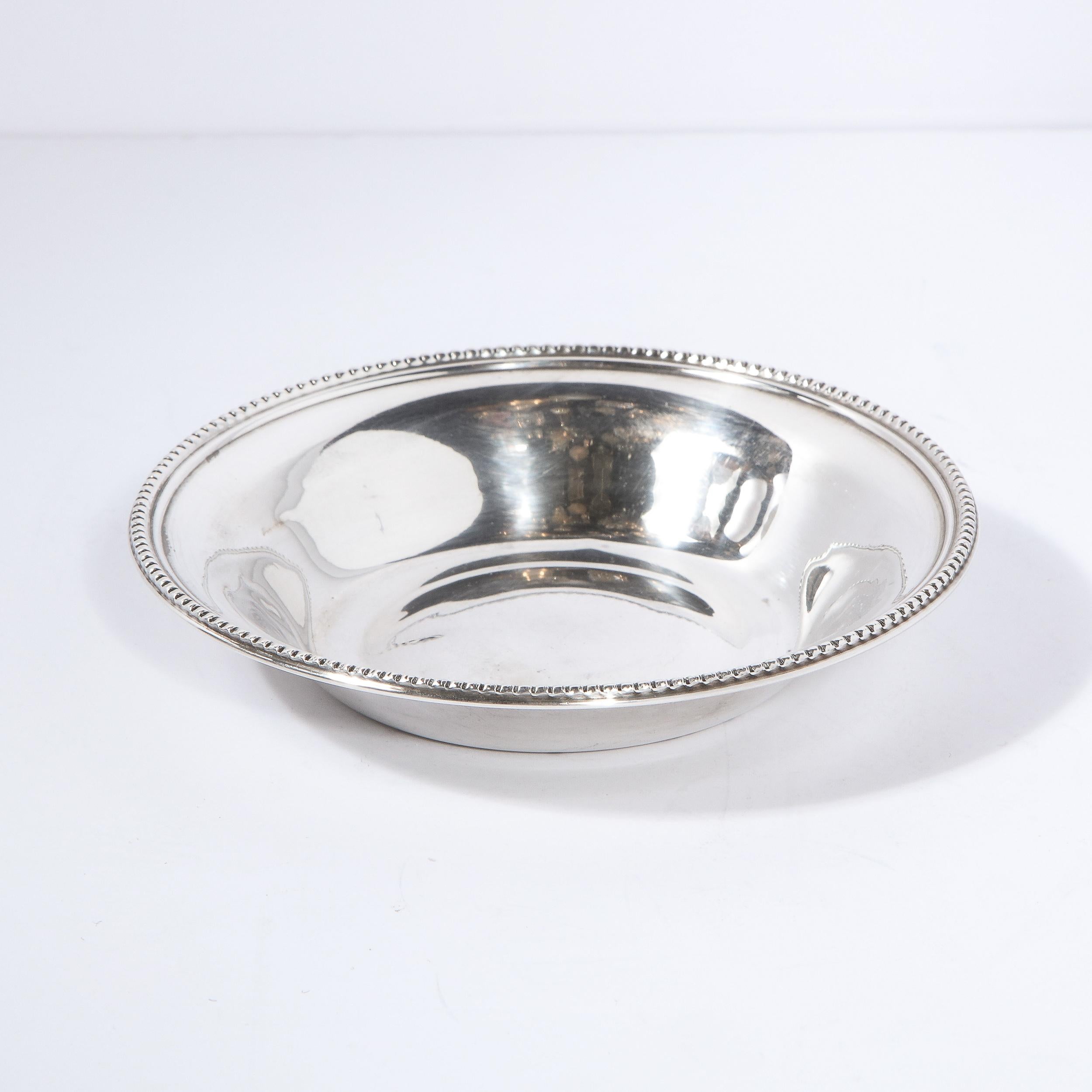 This beautiful Mid-Century Modern sterling silver decorative dish/ bowl was realized in the United States circa 1950. It features a circular bottom, gently rounded sides and a beaded perimeter all in lustrous sterling silver. With its clean