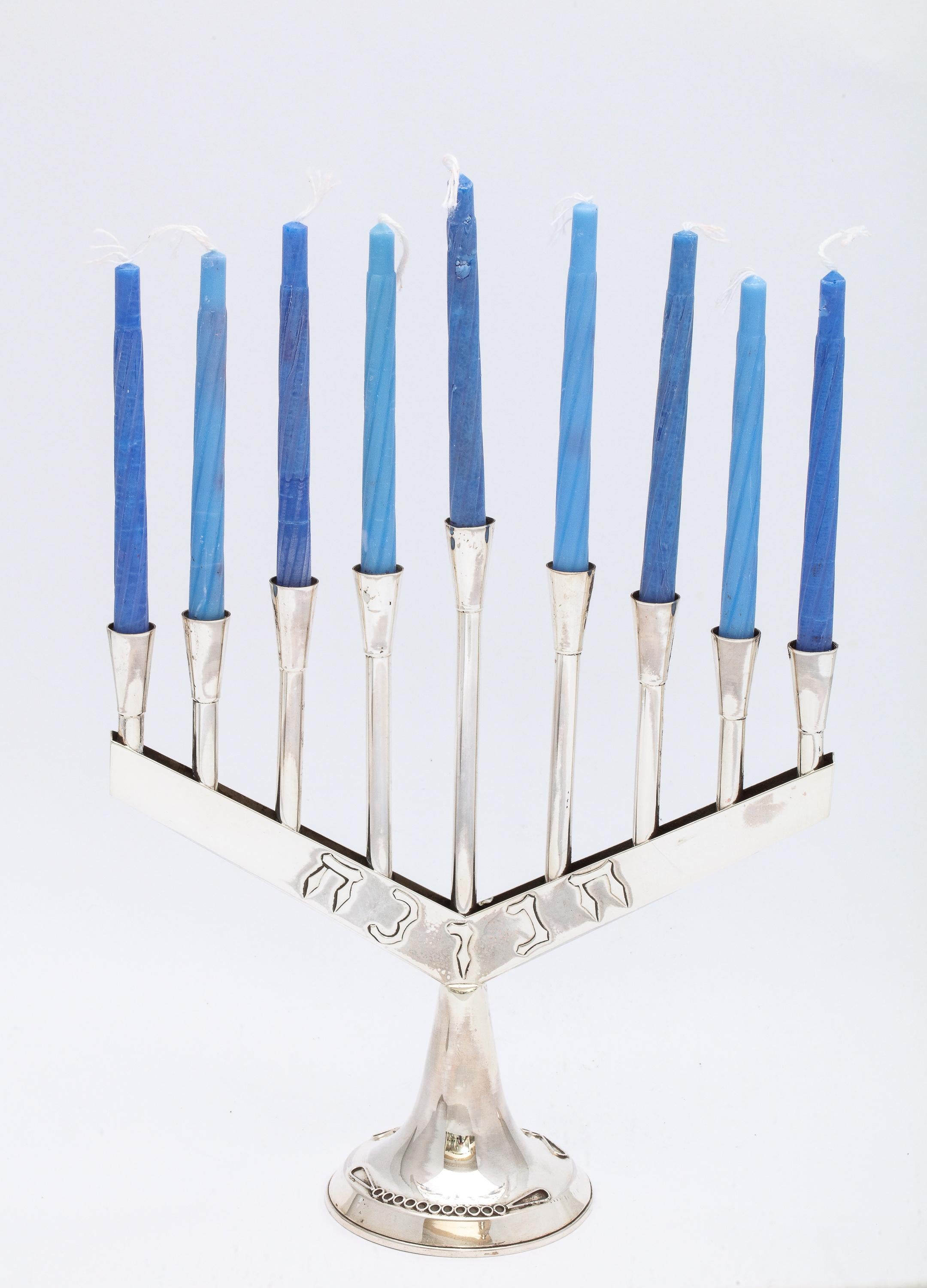 Mid-Century-Modern, sterling silver menorah, Israel, Ca. 1960's. Measures 7 inches high x 7 inches wide (at widest point x 2 1/2 inches diameter across base. Weighs 3.500 troy ounces. The word Chanukah (in Hebrew) is part of the design on the