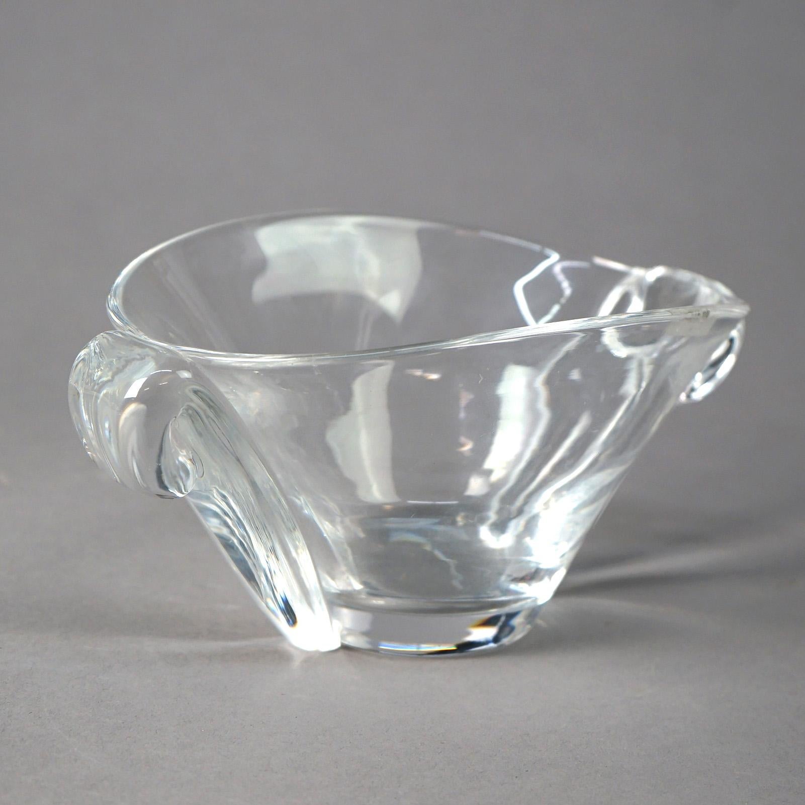 76260-UW A Mid Century Modern bowl by Steuben offers colorless art glass construction with flared form and having flanking stylized scroll handles, maker signed, c1950

Measures - 4.45