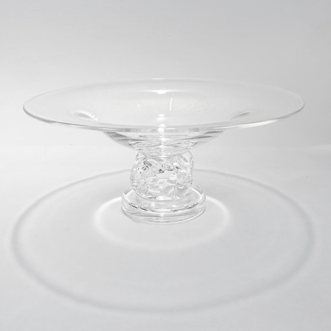 A fine Mid-Century glass pedestal bowl or tazza.

By Steuben.

Model no. 7884.

Designed by George Thompson.

With a wide shallow bowl supported by 4 arms on a disc shaped base.

Simply a wonderful piece of Steuben glass!

Date:
20th