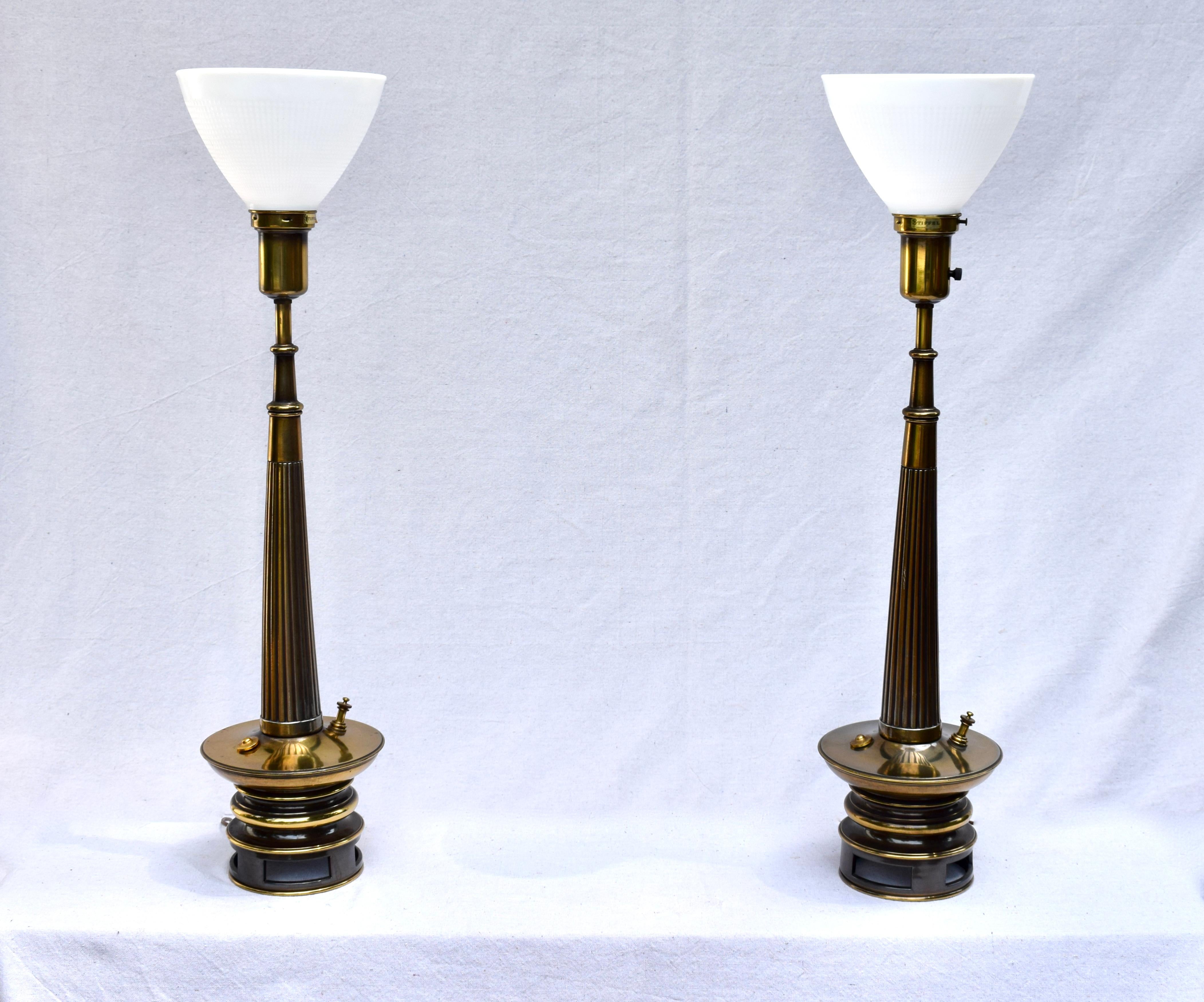 Ein Paar Transitional Mid- Century Modern Tischlampen von Stiffel.
Zu den Merkmalen gehören Stahlsockel in Gunmetal Gray mit sich nach oben verjüngenden, geriffelten Messingstielen und Fackelschirmen aus Milchglas. Die auffälligen original