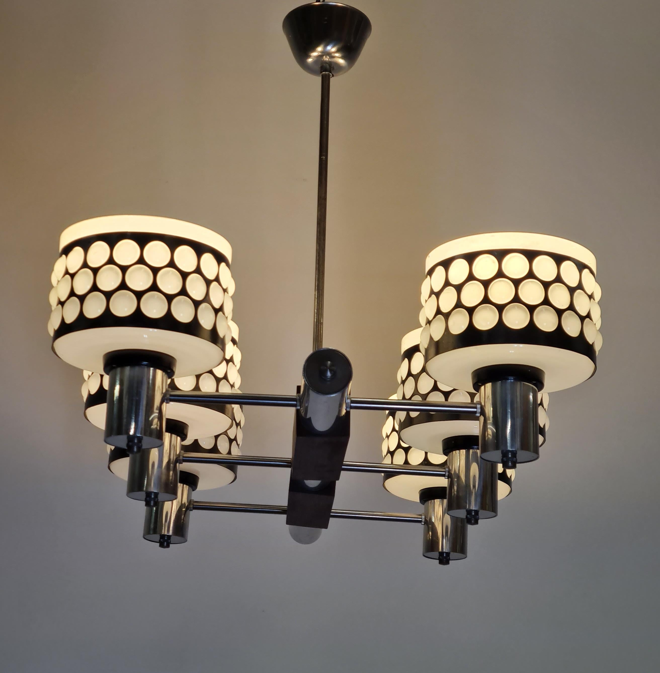 A modernistic Stig Lindström ceiling pendant manufactured by Lival Oy in Finland mid 1960s. The pendant features six light bulbs in milk-glass / metal shades on a chrome and teak base. A design growing in popularity with its nostalgic touch and fast