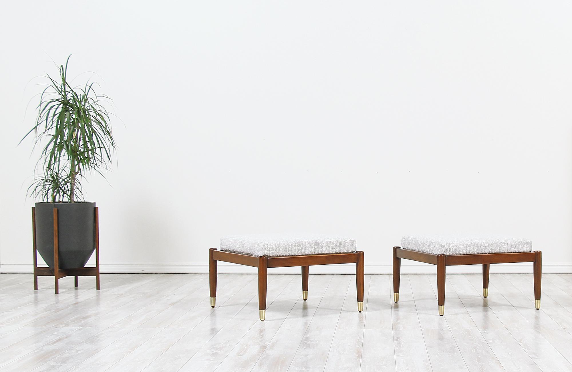 A pair of elegant modern stools designed by Folke Ohlsson for DUX of Sweden in Sweden circa 1950s. This stylish pair of stools are made of solid walnut wood with brass sabots in all four legs. Both stools have been refinished and reupholstered by