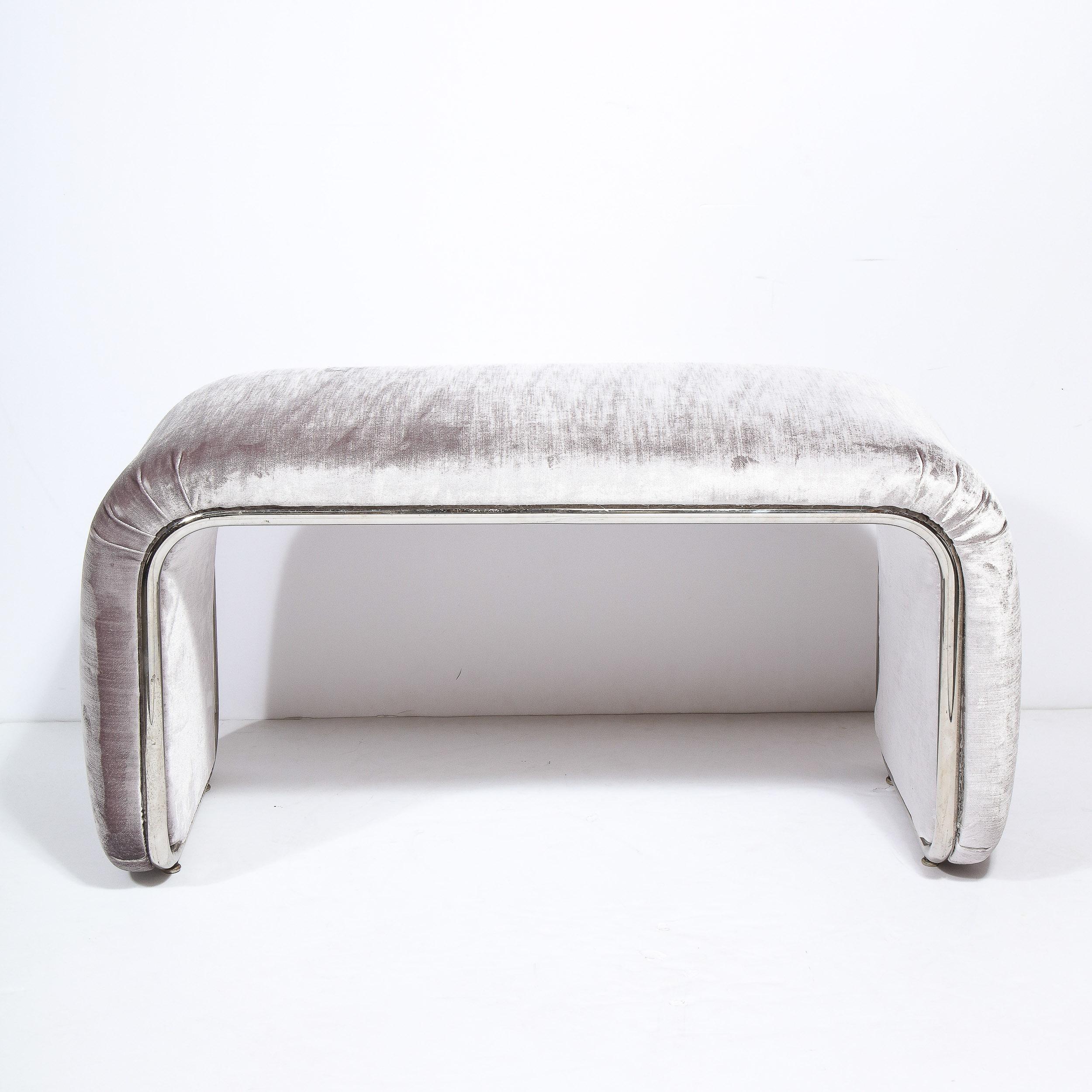 This glamorous Mid Century Modern waterfall bench was realized in the United States circa 1970. It features a dramatic streamlined form newly reupholstered in a beautiful smoked velvet. The perimeter of the piece is wrapped in tubular chrome with