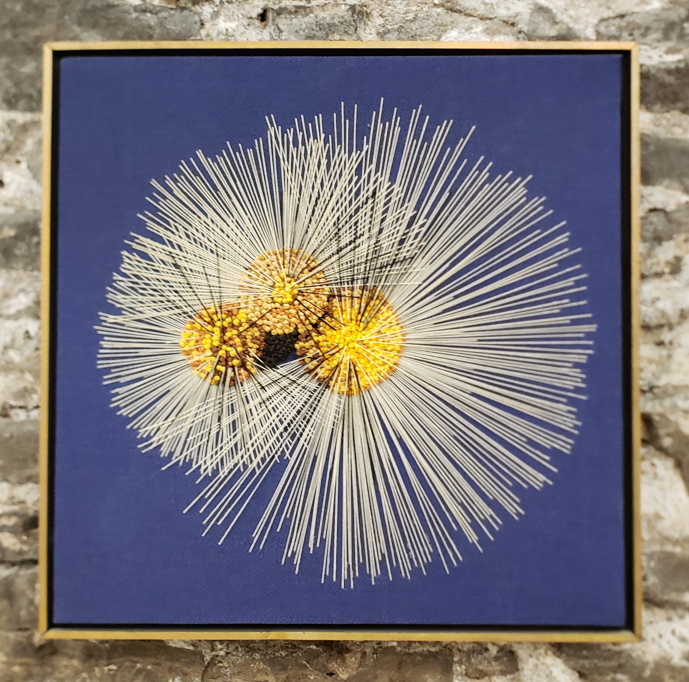 This artisan made framed wall sculpture is unsigned, but presumed to have originated from Canada and date to approximately 1970 and done in a Mid-Century Modern style. The sculpture is done with white string and a series of yellow wood on blue