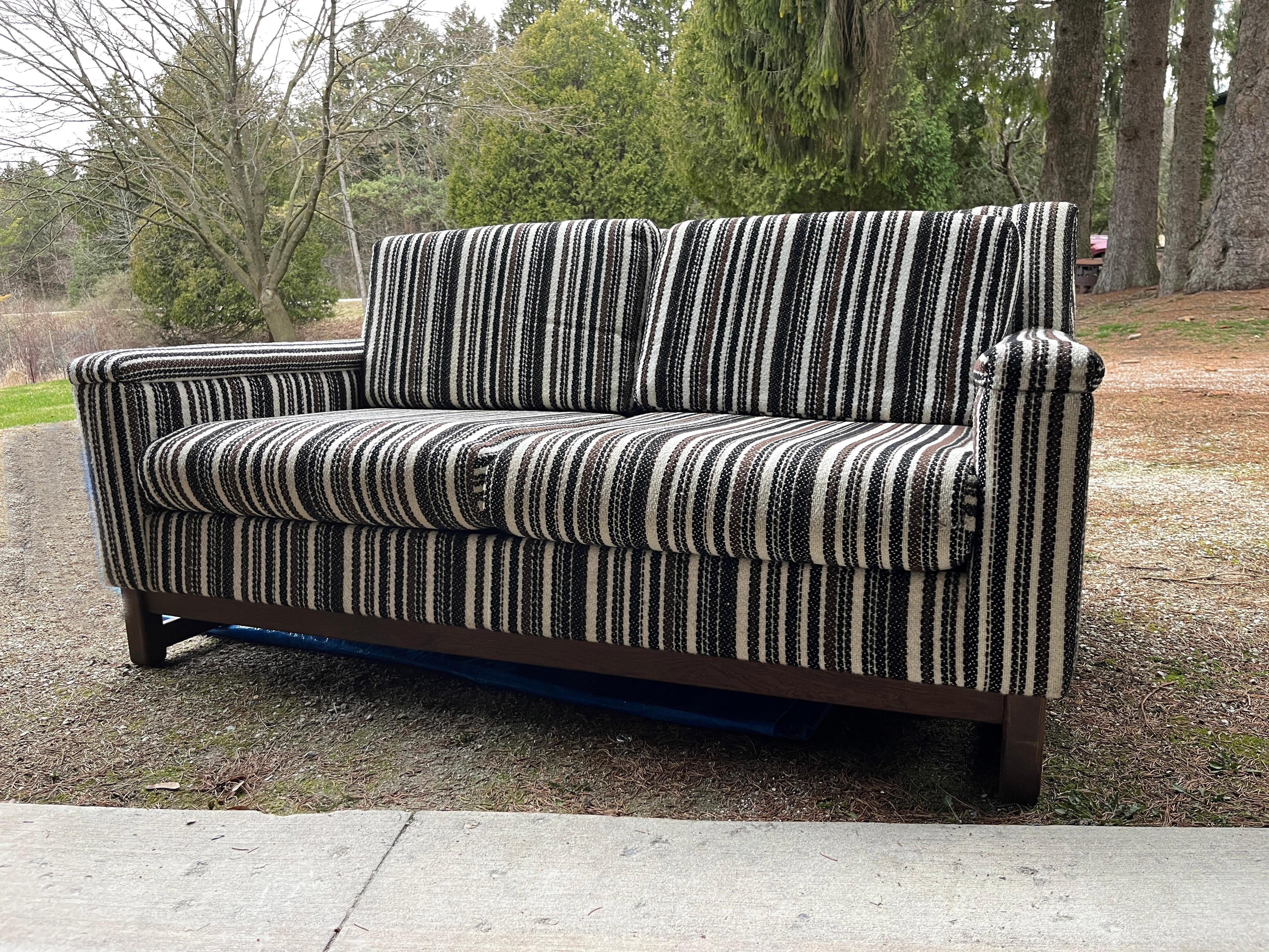 What a find. Mid-Century Modern loveseat made by Selig of Monroe from 1965. This is a two-seat with black, brown and cream striped polyester upholstery and solid wood base. Very solid and well-crafted piece. Original tags in place.

Designer