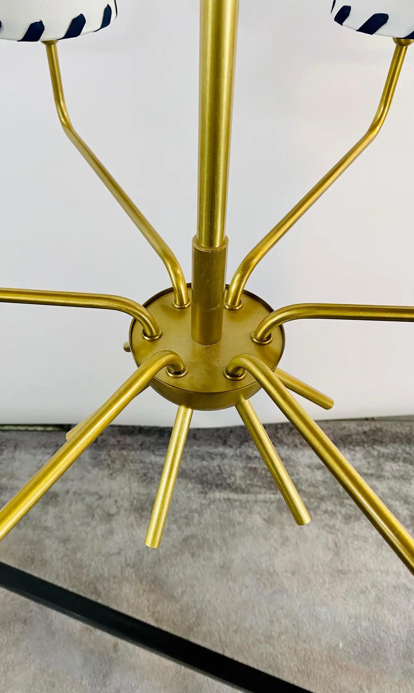 An elegant Mid-Century Modern sputnik gilded chandelier. Featuring a sleek design, the chandelier is embellished with custom made cone shape shades in white with back stitching motifs covering 6 candelabra lights. The Sputnik MCM Chandelier bottom