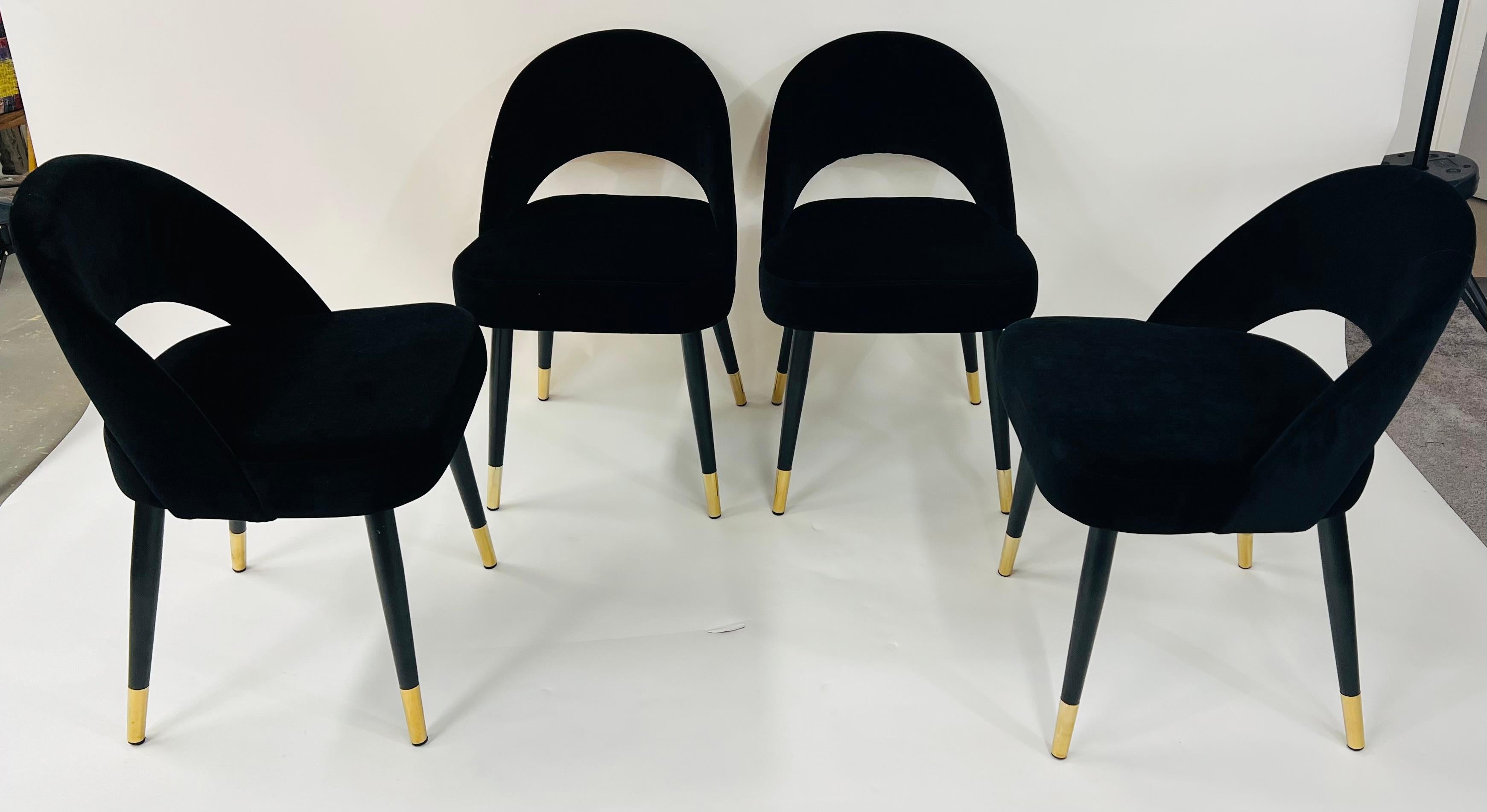 A set of four Mid-Century Modern style barrel chairs. The stylish chairs are made of black suede upholstery and raised on four tapered legs decorated with brass. Comfortable and also Modern, timeless and fashionable, the set of chairs will elevate