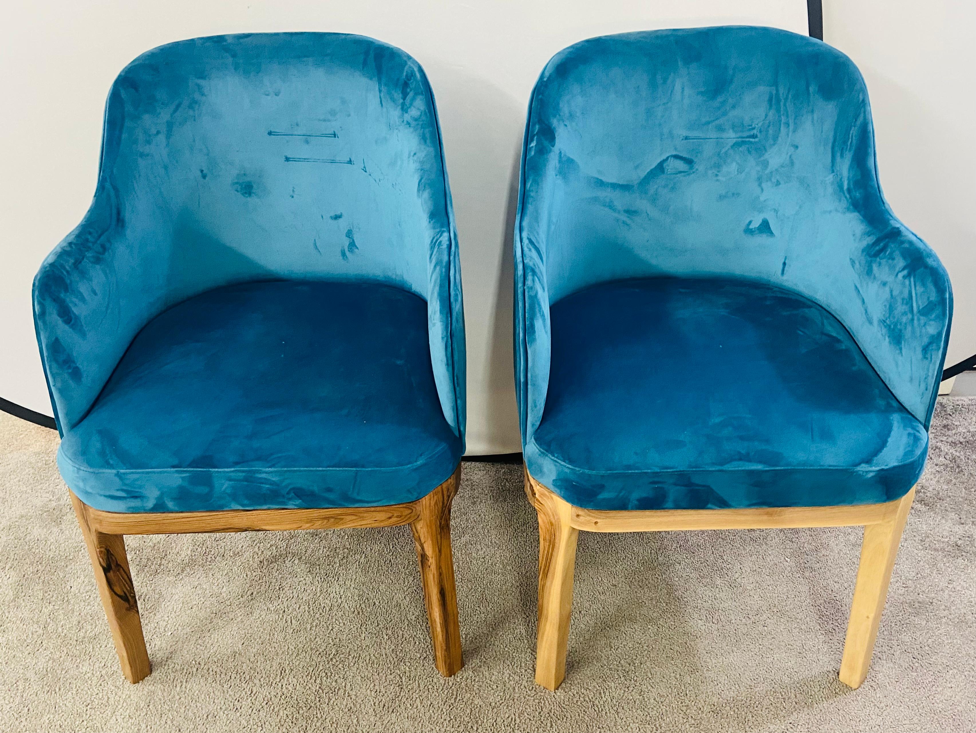 A stylish pair of Mid Century Modern style barrel chairs. The chairs feature a recent upholstery in an electric vivid blue velvet. a highly desirable and fashionable color. The high quality chairs are made of walnut wood. The natural color of the