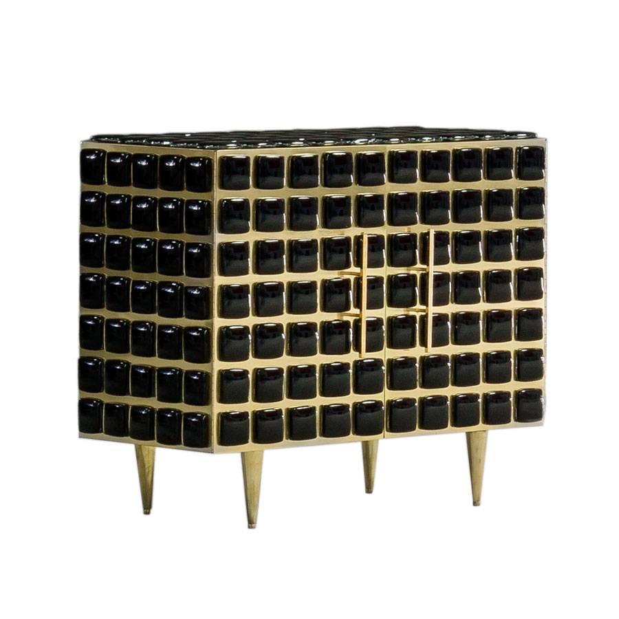 Midcentury style pair of Italian sideboards designed by L.A.Studio. Structure made of solid wood covered with brass and black glass pieces.
Composed of two folding doors with one shelve inside and four conical legs made of solid brass. Manufactured