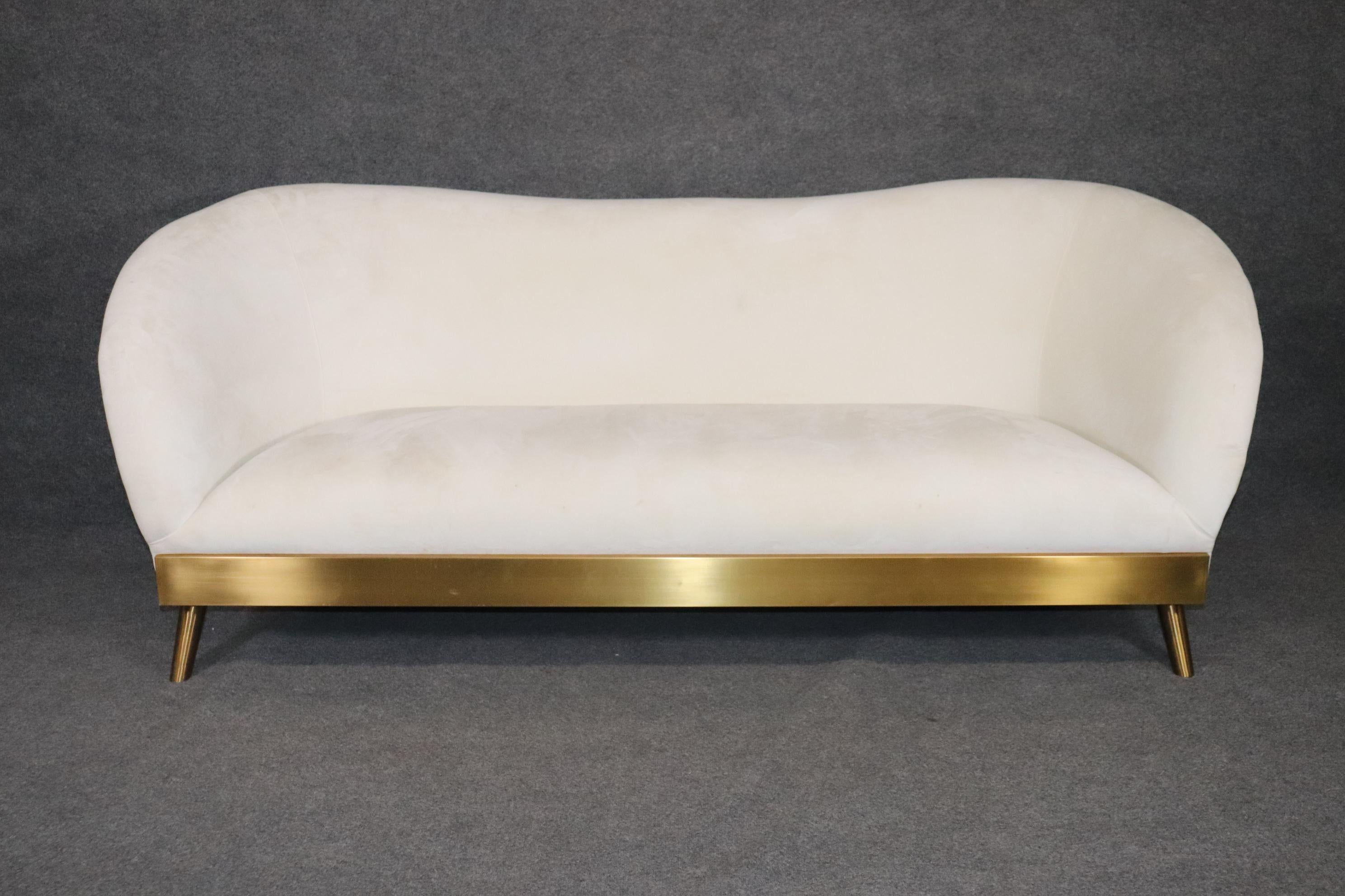 This is a beautiful and very chic mid century modern style 2000s era sofa with brass elements. The sofa is upholstered in what I believe is a chenile and very very soft and almost as soft as rabbit fur. The upholstery is used so there are some minor