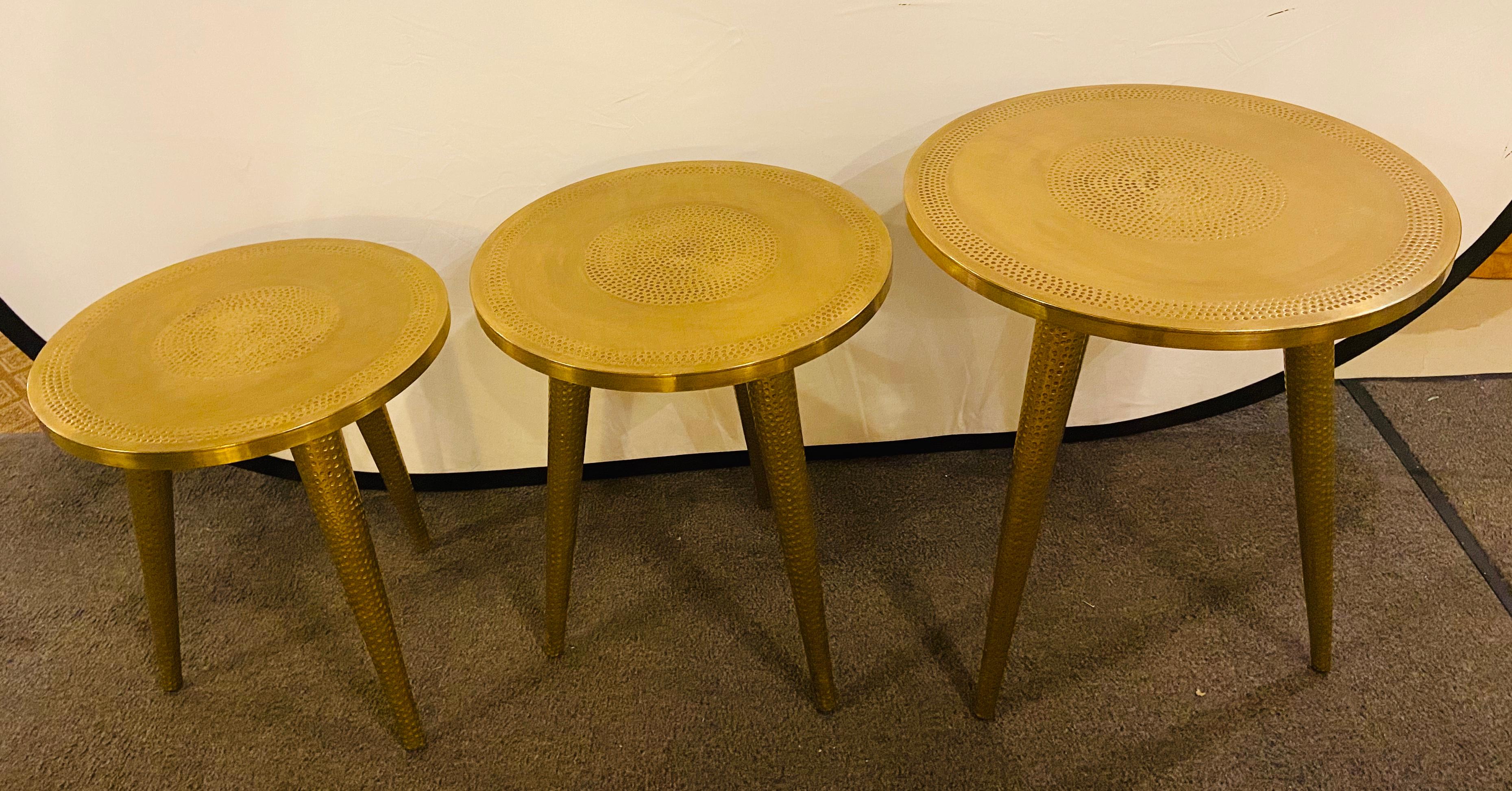 Set of three hand-hammered brass Mid-Century Modern style nesting side tables. Each table features beautifully handcrafted base and circular tops. The set of nesting tables is an elegant touch to any living environment and style each having tapering