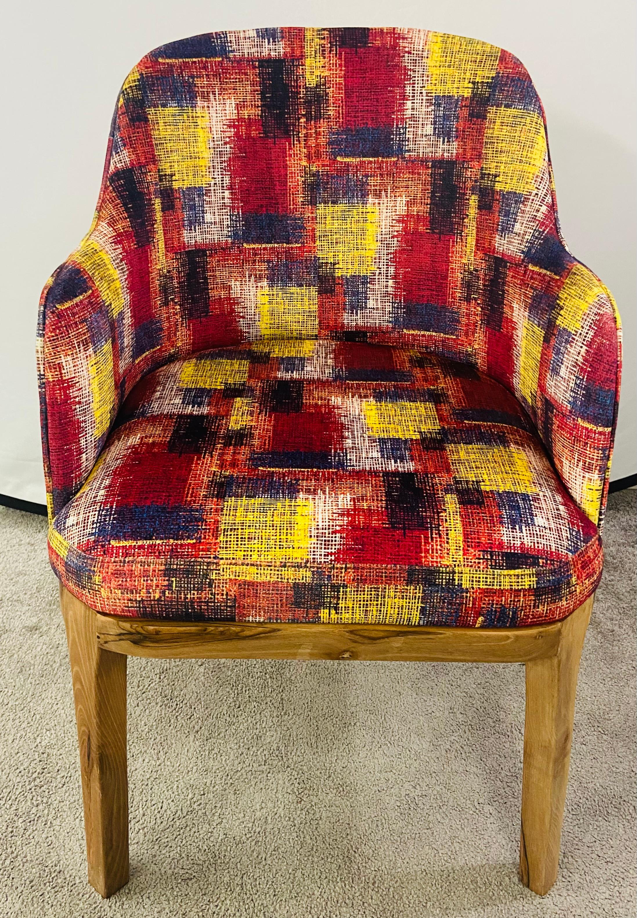 A stylish pair of Mid Century Modern style barrel chairs. The chairs feature a recent upholstery in vivid dark blue, yellow and cranberry colors. The high quality chairs are made of walnut wood. The natural color of the walnut wood showing burl