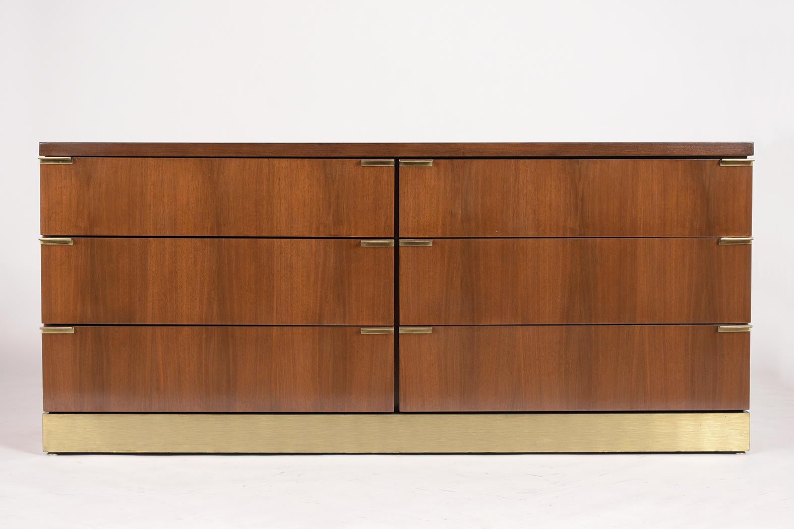This Mid Century style Credenza by Glenn of California has been professionally restored and newly stained in a dark walnut color with a semi-gloss lacquered finish. The credenza has six large drawers each with two brass pull handles on each side,