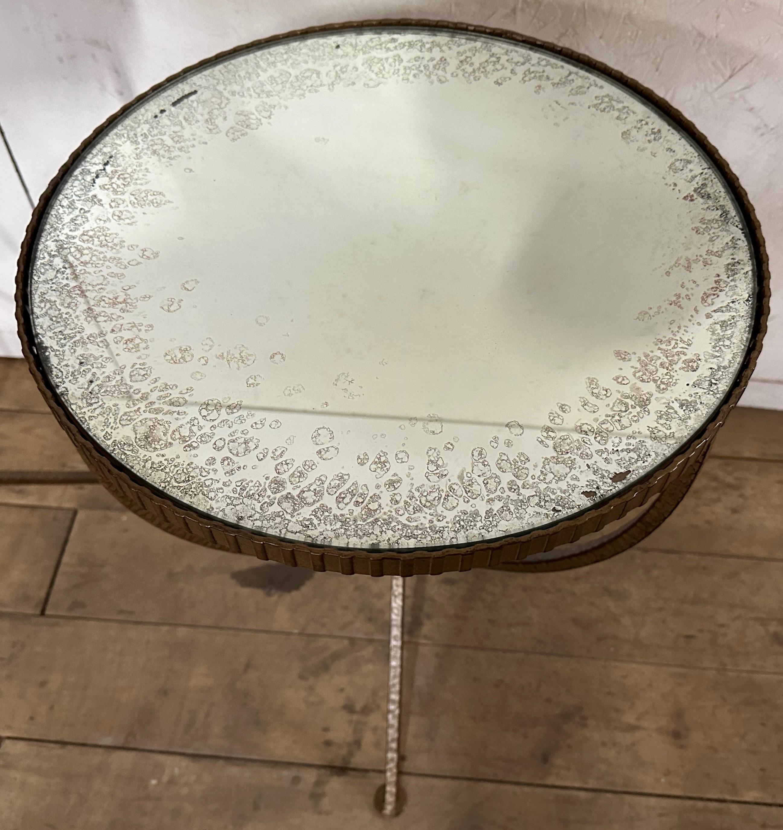 The Mid-Century Modern Round gold toned table has a hammered texture iron frame with antiqued mirror to give it character. This side, end table or accent table has the elegance in the manner of an Hollywood Regency or neoclassical table.
The table