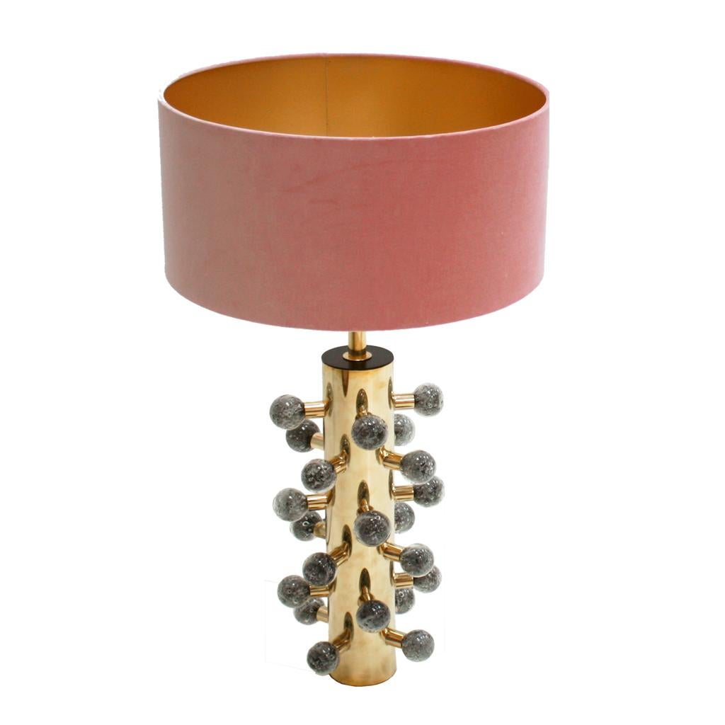 Sculptural Italian table lamp with cylindrical structure made of polished brass and grey Murano glass sphere.
Circular lampshade made of pink cotton velvet fabric.