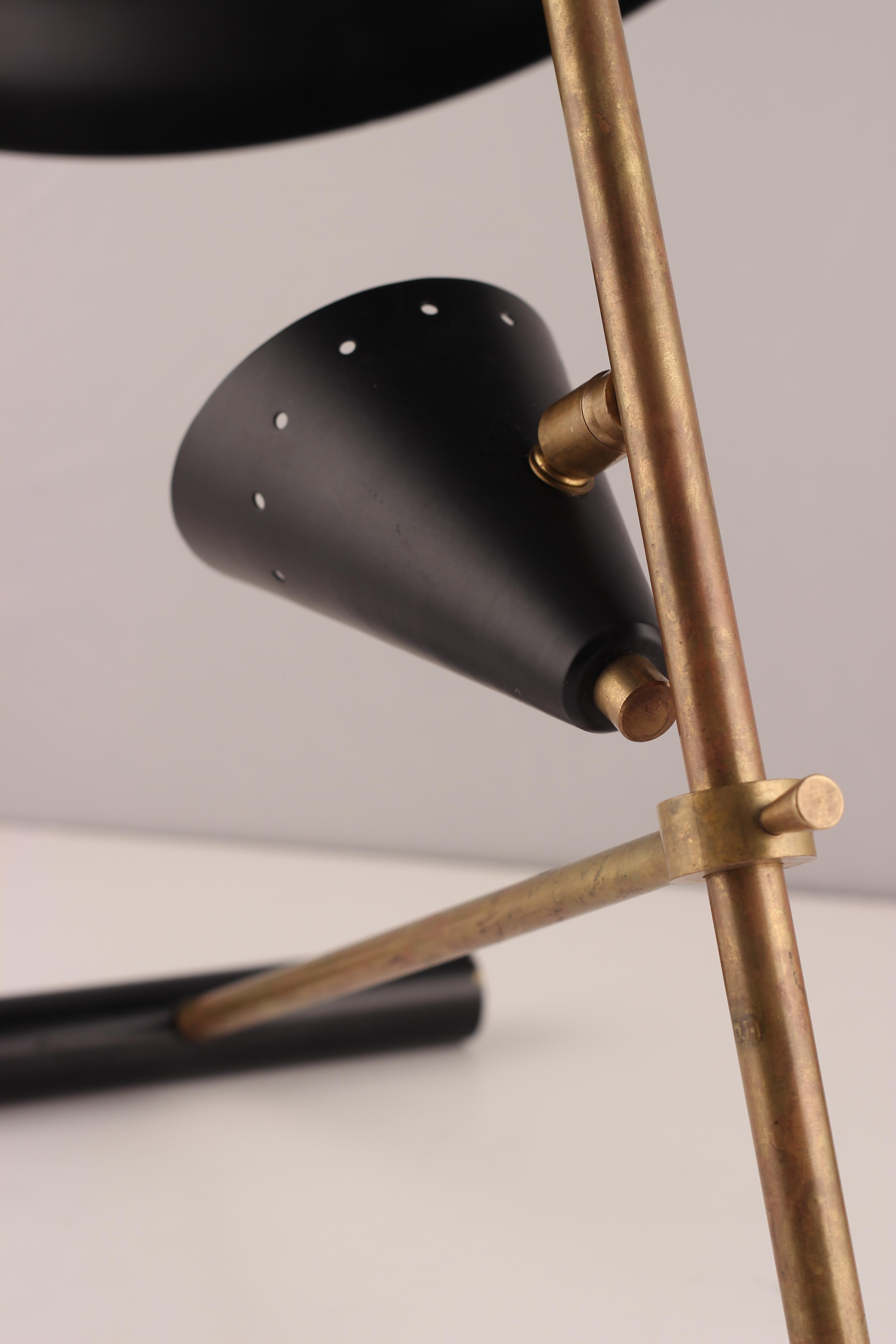 A Mid-Century Modern style Italian table lamp or desk lamp made of brass and black lacquered metal, with two directional designed lampshades, with one bulb holder in the smaller shade. We believe this piece to be of recent 21st century production