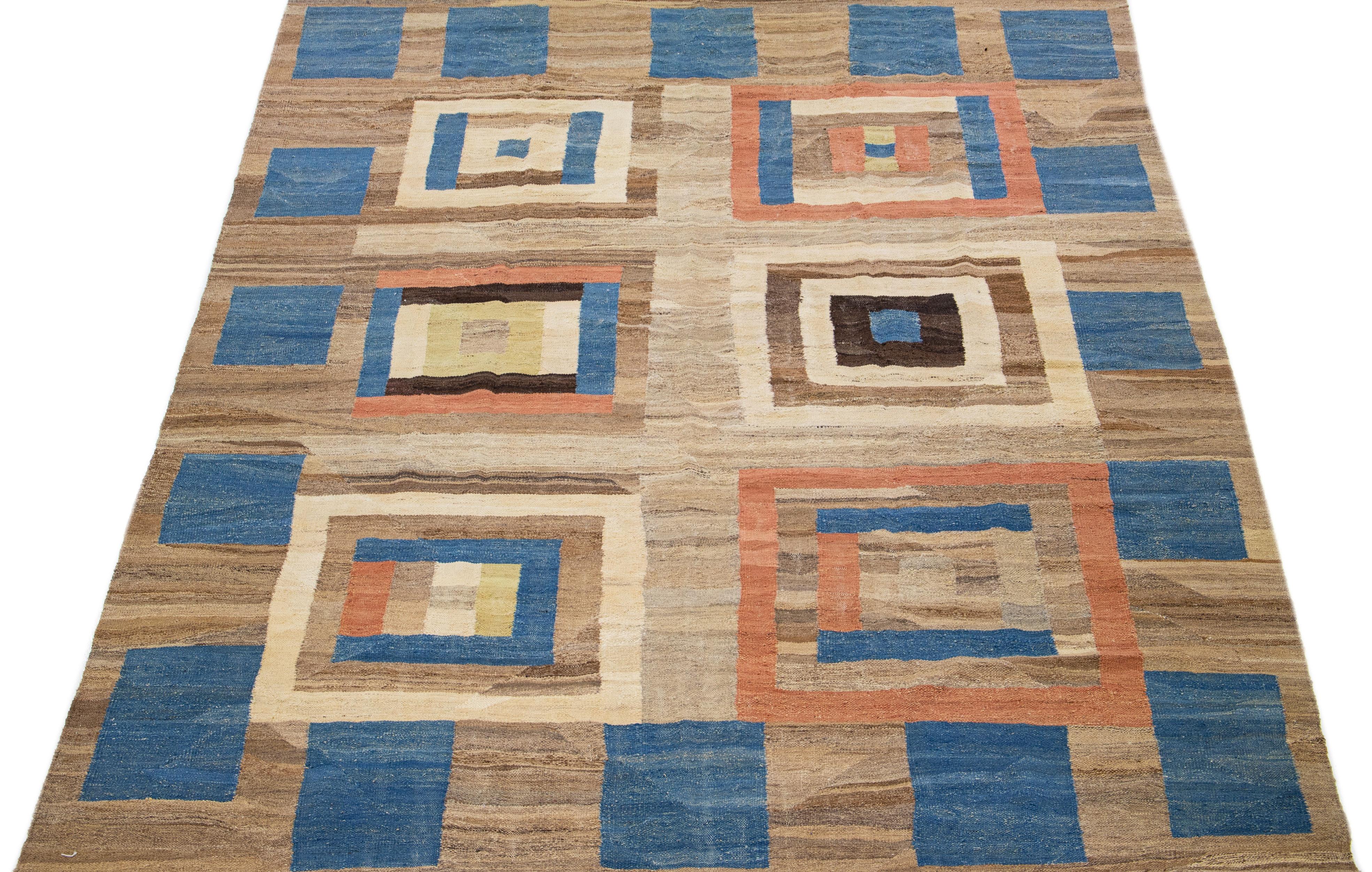 Beautiful Contemporary Kilim wool rug with a brown color field. This flatweave rug features a gorgeous geometric deco design in beige, orange, and blue accents. Combining brown, beige, orange, and blue creates visually stunning geometric shapes,