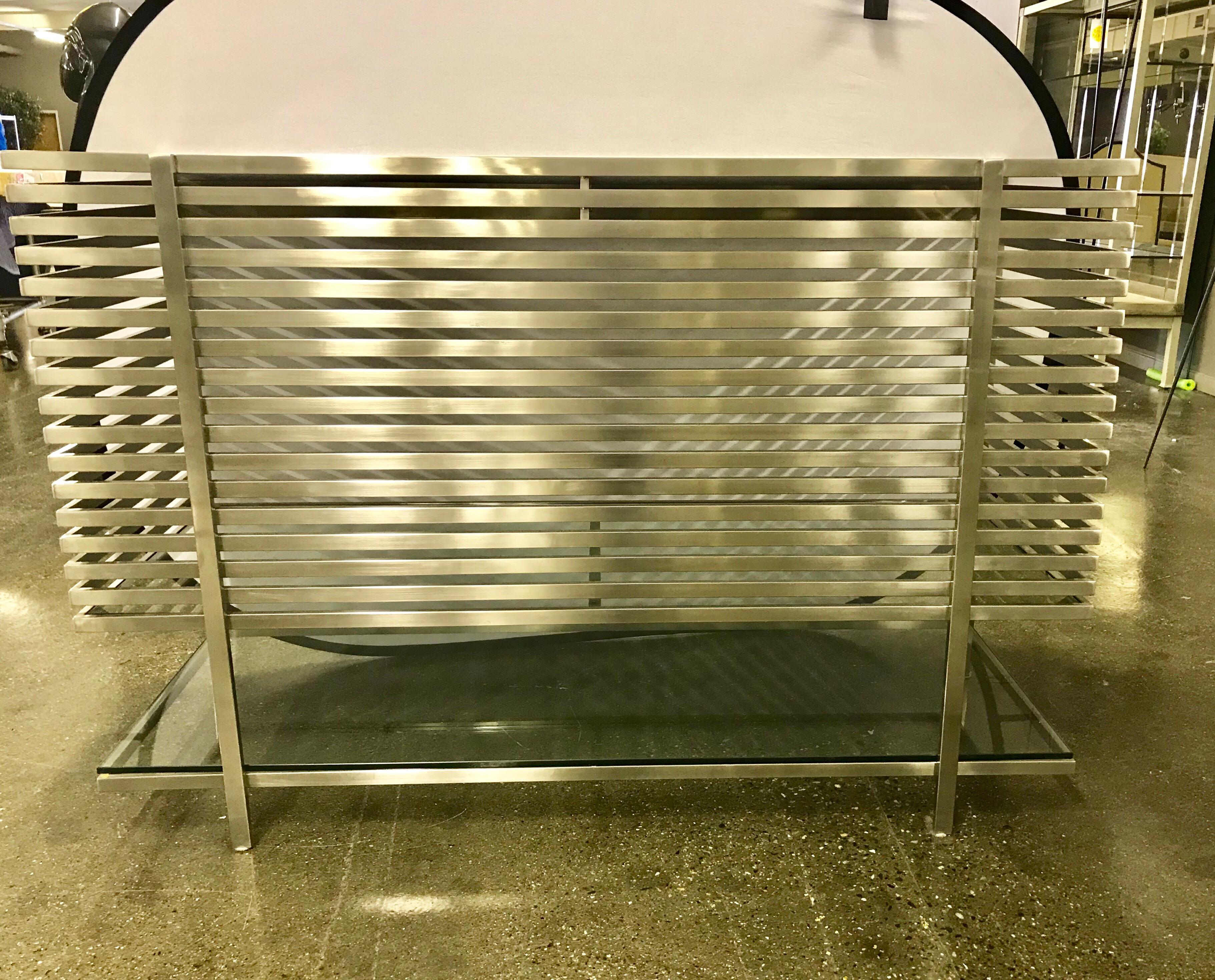 Architecturally inspired laser cut steel and chrome bar has a black glass top and clear glass shelving on the bottom. The perfect aesthetic for your contemporary or midcentury home. Retailed new for over $10,000.00. Mint condition.