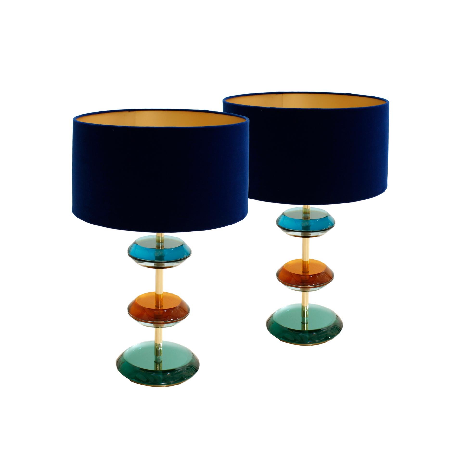 Pareja de lámparas de mesa diseñadas por L.A. Studio. Presenta una estructura de latón macizo adornada con piezas de cristal de colores de Murano. Fabricadas en Italia, se complementan con pantallas circulares de lana bouclé blanca.

Dimensiones con