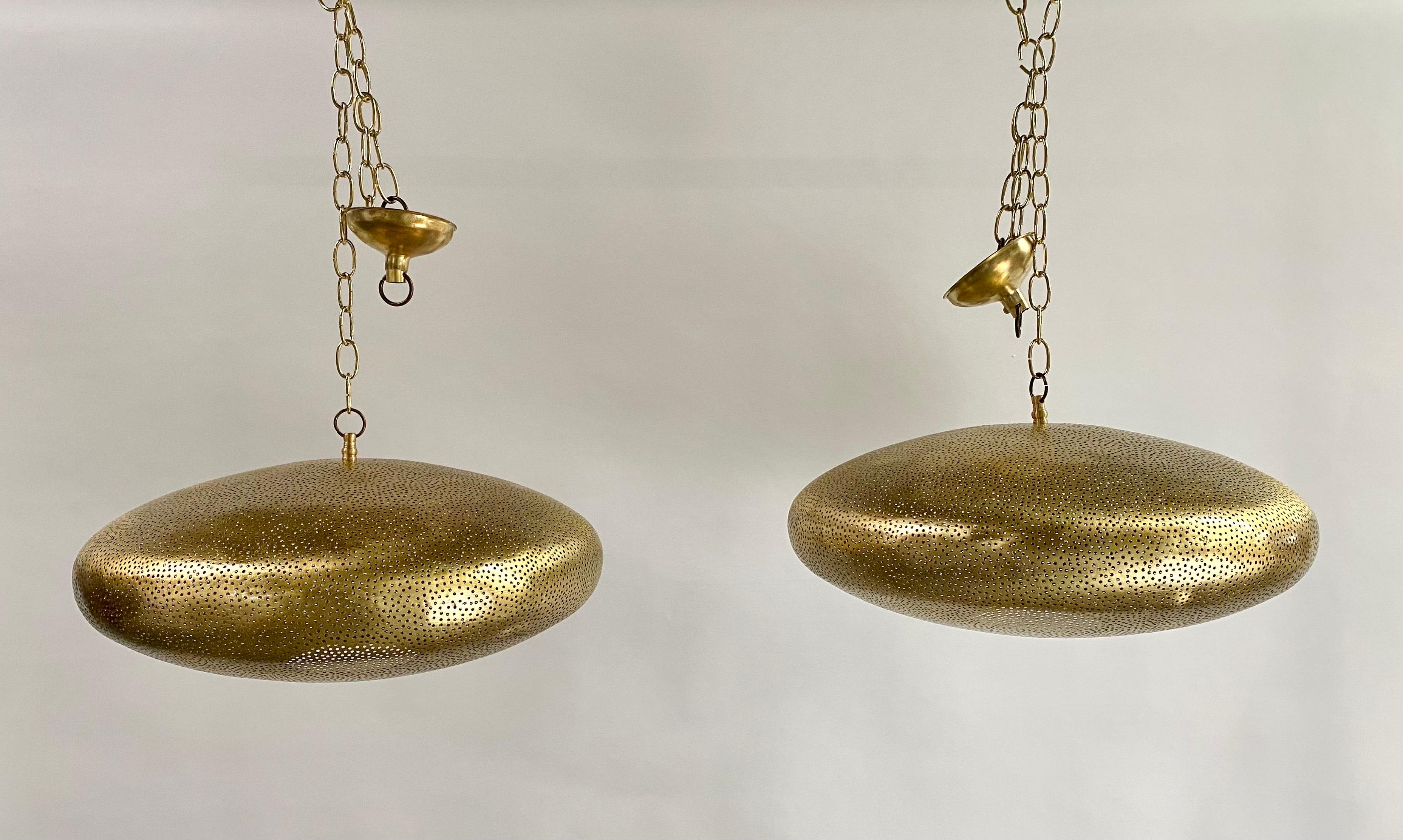 A pair of Mid- century Modern style all brass pendants or lanterns. Featuring a spaceship oval shape, these stylish pair of pendants are handmade of high quality brass and finely hand-tooled producing a soft ambient lighting perfect to elevate the