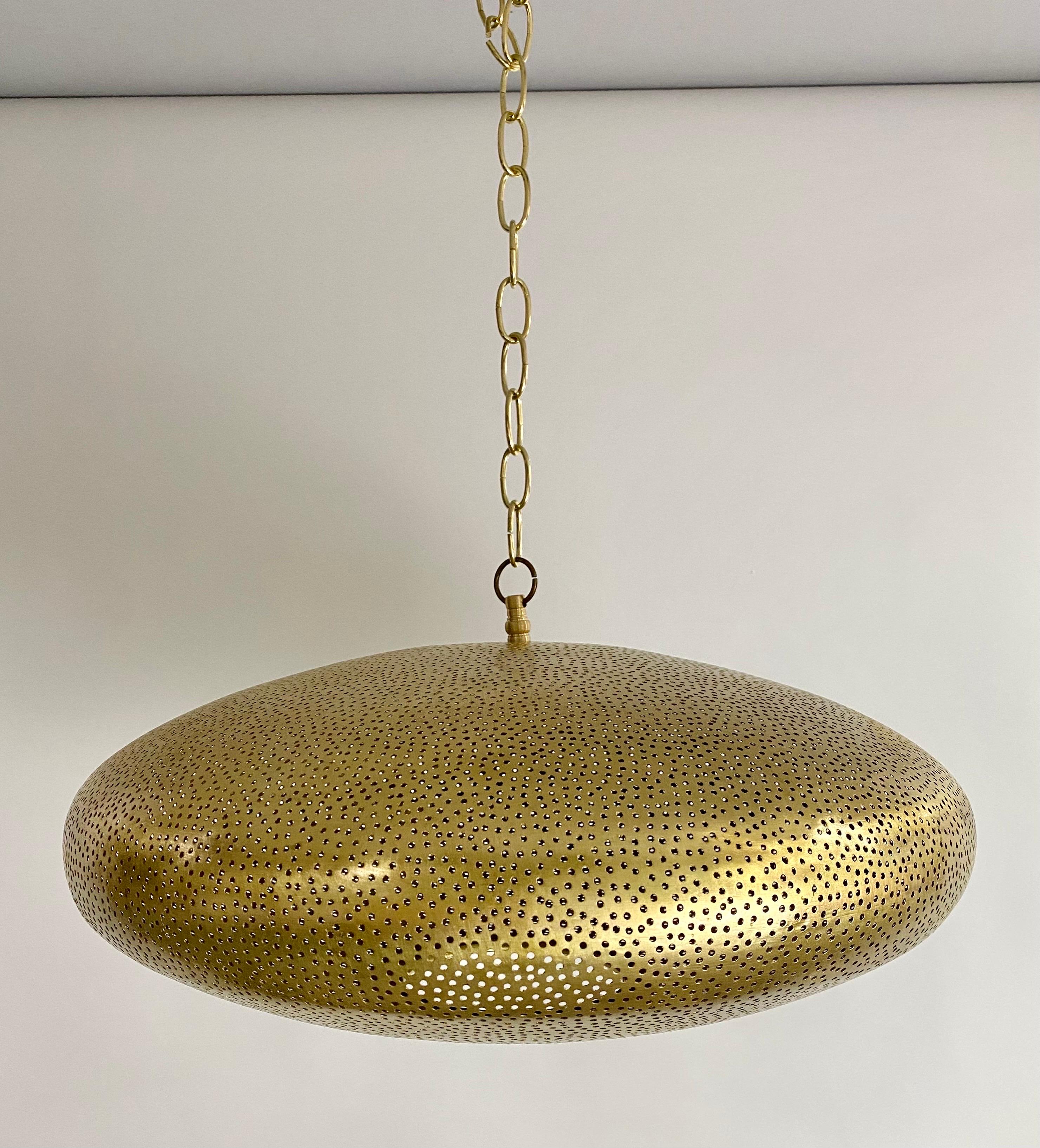 A Mid-Century Modern style all brass pendant or lantern. Featuring a spaceship oval shape, this stylish pendant is handmade of high quality brass and finely hand-tooled producing a soft ambient lighting perfect to elevate the mood and complement