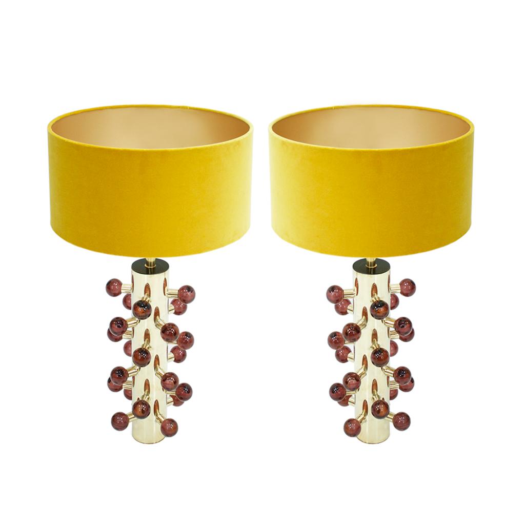 Contemporary maximalist pair of brass table lamps, a stunning blend of modern design and opulence. This exquisite lamp features a cylindrical Polished brass structure adorned with spherical Murano colored in Burgundy glass pieces, adding a touch of