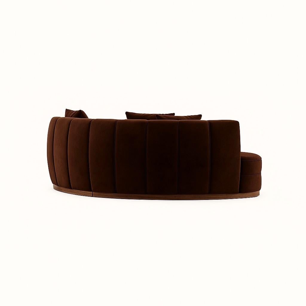 Interprétation sculpturale de l'élégance moderne du milieu du siècle, ce canapé incurvé est revêtu d'un riche velours chocolat qui ajoute de la profondeur et de la chaleur à tout décor. La silhouette ajustée présente des détails de canaux verticaux