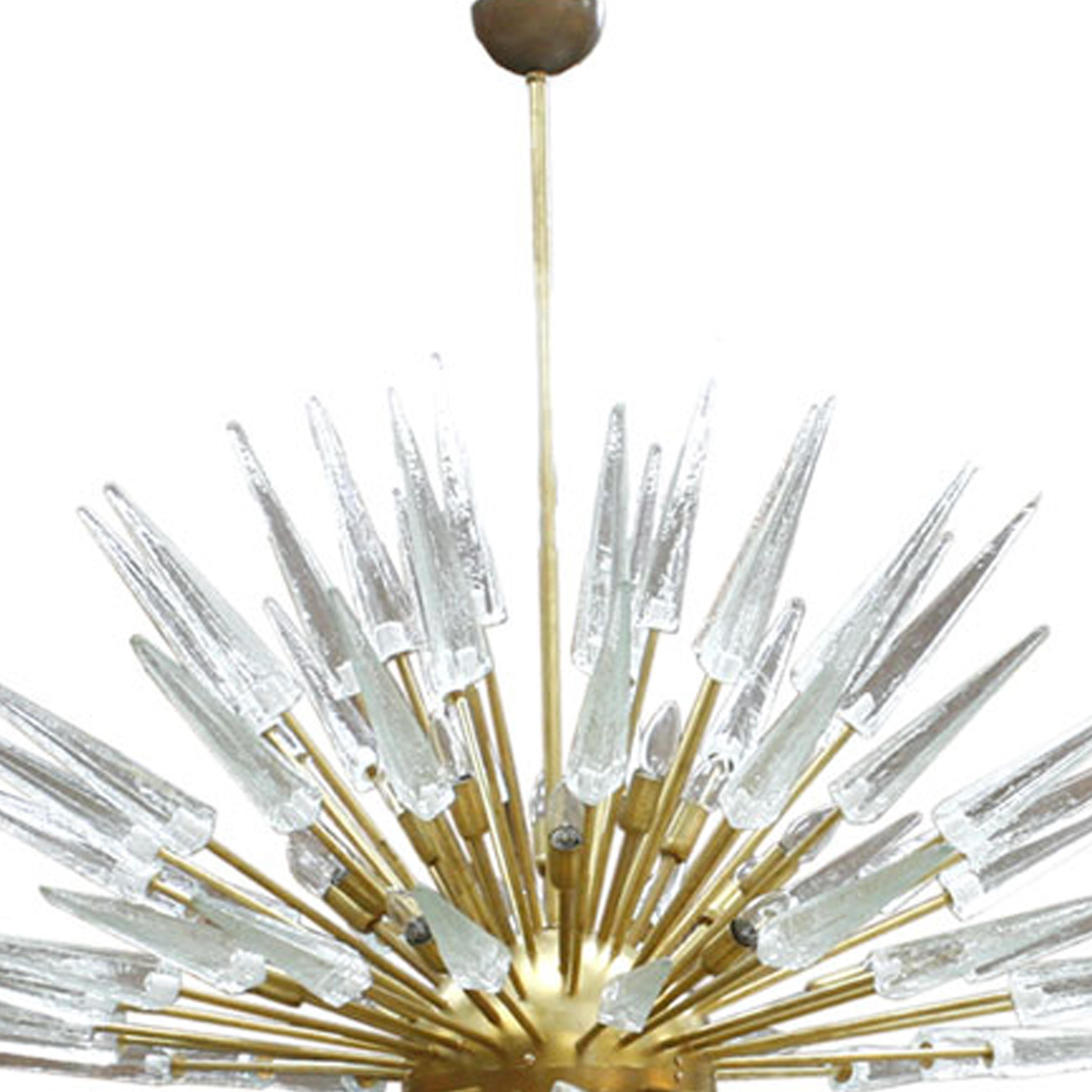 An impressive and very large Sputnik chandelier made of clear Murano glass shards and brass rods fixed to a central brass lacquered orb. Bulbs are coming from the brass rods ends and hidden between the hallo of glass spikes. Made in Italy.

 
Our