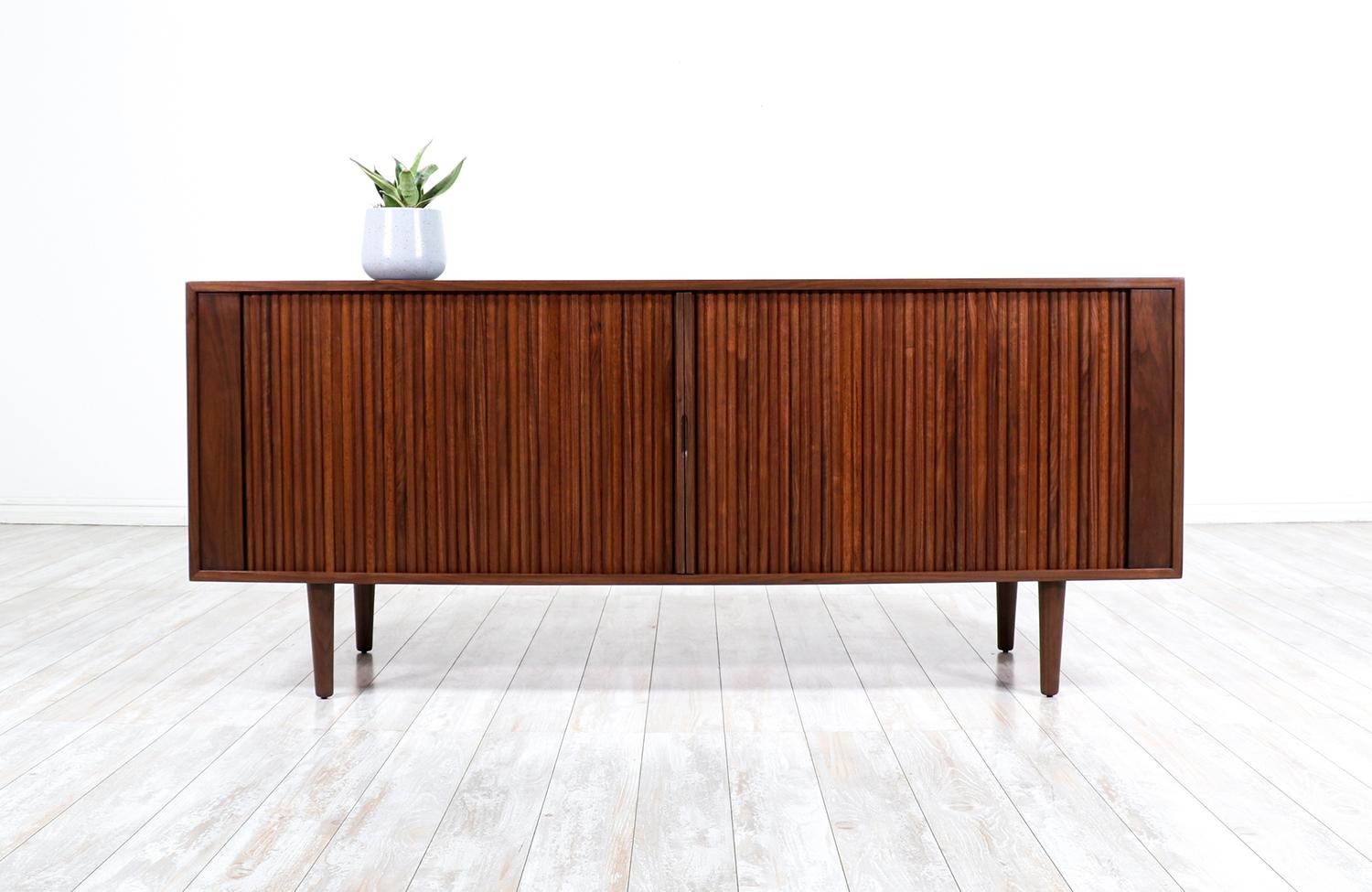 Introducing our first-ever modern credenza designed and crafted by Danish Modern L.A.'s artisans' house in Los Angeles, CA. Our skillfully crafted credenza showcases a solid American walnut case that features two tambour-doors with carved, recessed