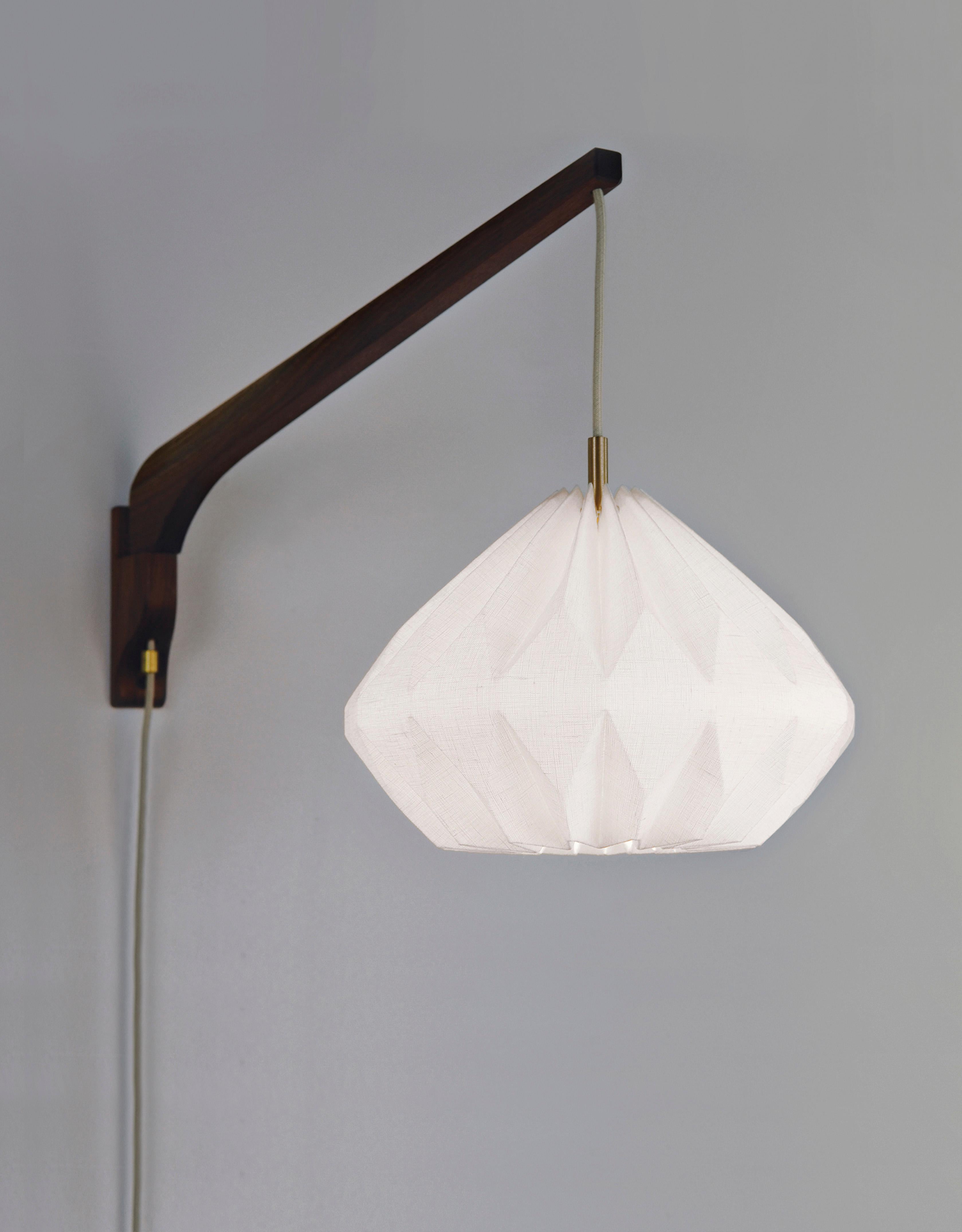 Made of a linen shade with a beautifully handcrafted wooden swing arm, this Mid-Century style wall lamp will bring to your interior an interesting and functional work of art. The origami-inspired shade has an open bottom that provides an extra flow